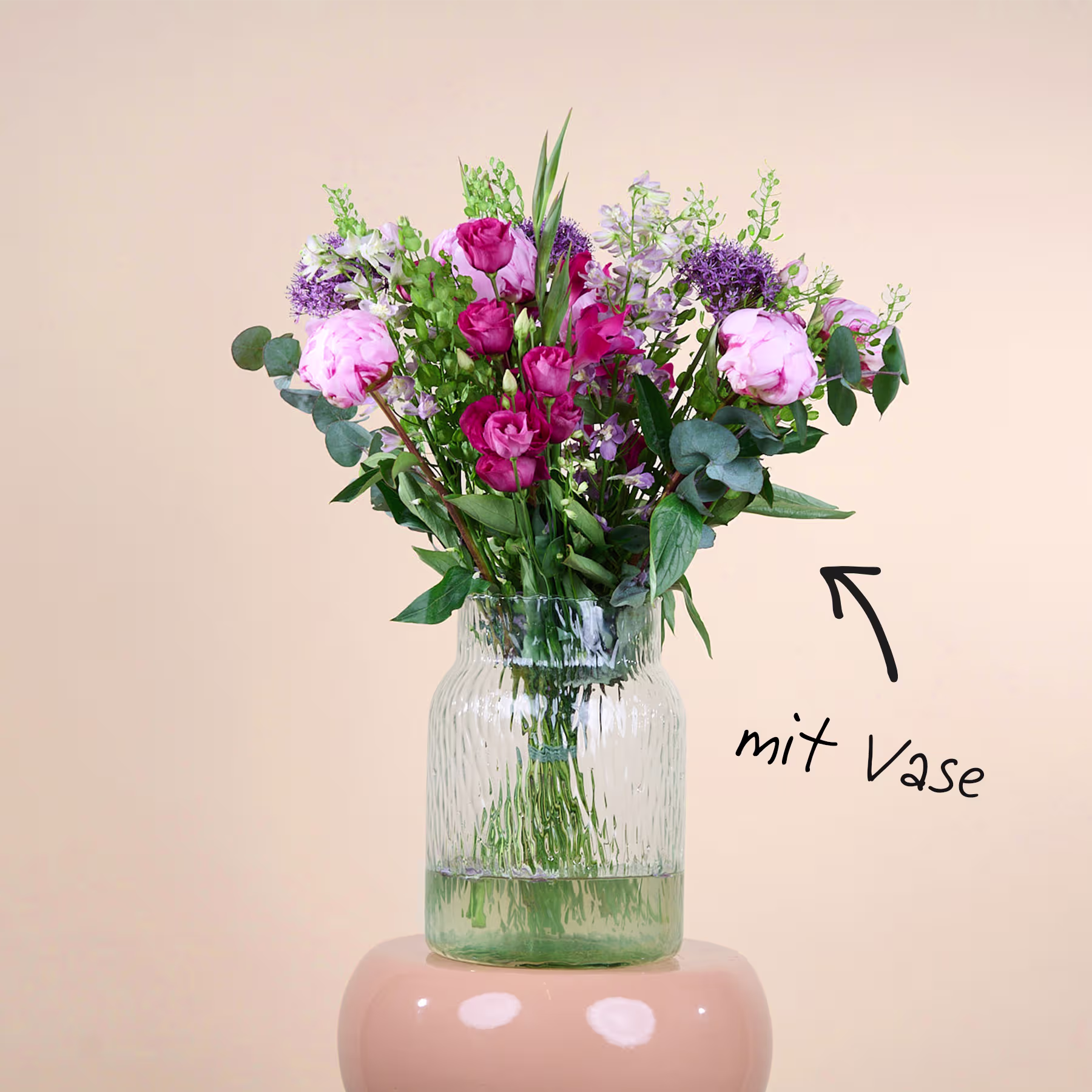 Ein leuchtender Strauß rosa und violetter Blumen in einer Glasvase steht auf einem hellen Hintergrund. (Beschreibungstext KI-generiert)