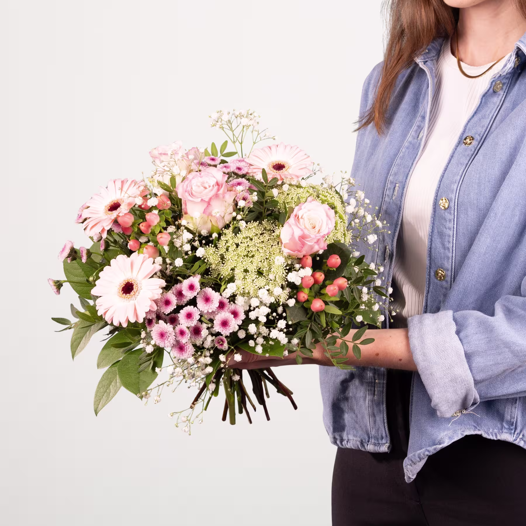 Ein leuchtender Strauß rosa und weißer Blumen, darunter Rosen und Gerbera, steht im Vordergrund vor einem sanften blauen Hintergrund. (Beschreibungstext KI-generiert)