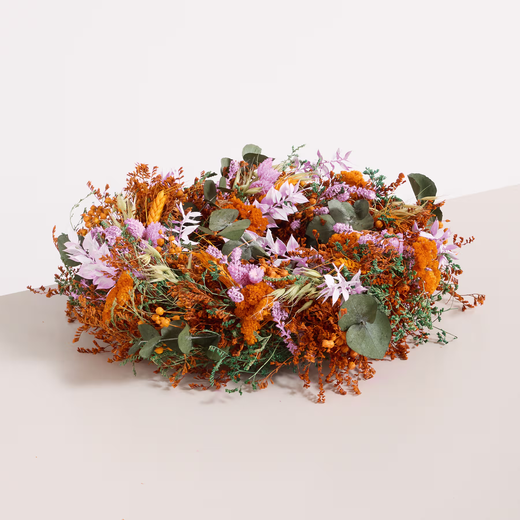 Ein lebendiges und farbenfrohes Arrangement aus verschiedenen Herbstblumen, Blättern und Laub, das auf einer schlichten Oberfläche ruht. (Beschreibungstext KI-generiert)