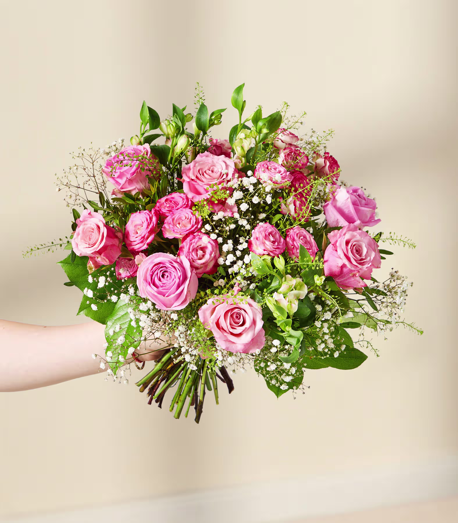Ein leuchtender Strauß aus rosa und roten Rosen, umgeben von üppigem Grün und zartem Schleierkraut, vor einem schlichten, hellen Hintergrund. (Beschreibungstext KI-generiert)