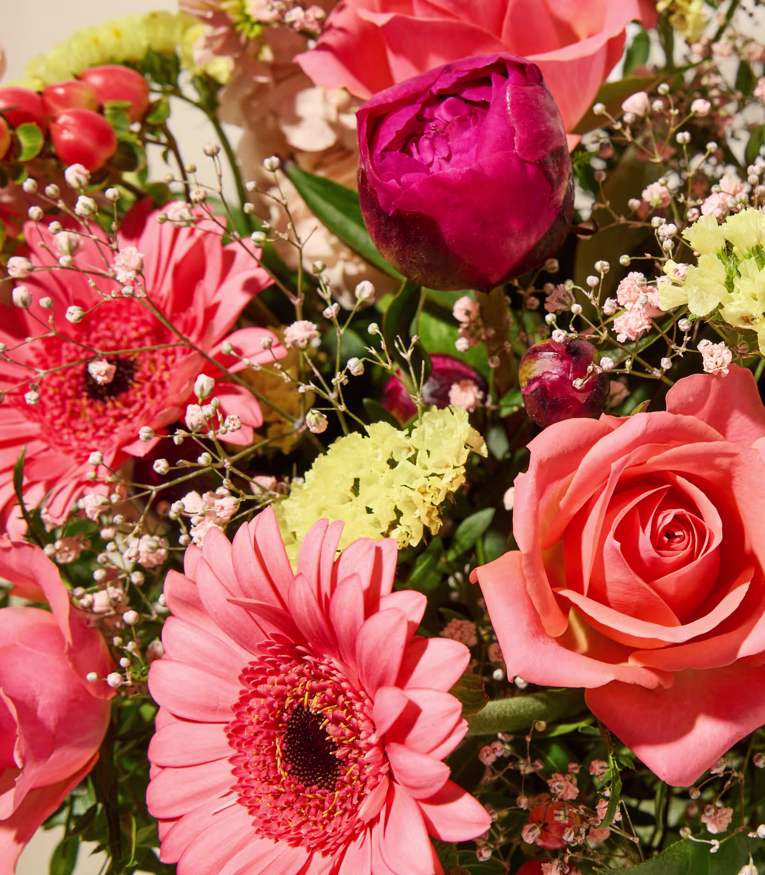 Ein lebhafter Blumenstrauß aus verschiedenen Blumen, darunter rote und rosa Rosen, rosa Gerbera-Gänseblümchen und andere dazu passende Blüten, vor einem weichen, verschwommenen Hintergrund. (Beschreibungstext KI-generiert)