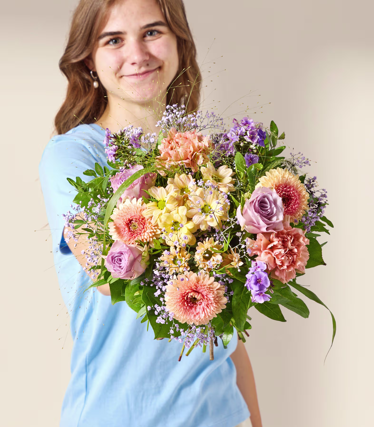 Eine junge Frau in einem blauen Hemd hält einen farbenprächtigen Strauß bunter Blumen vor einem schlichten, hellen Hintergrund. (Beschreibungstext KI-generiert)