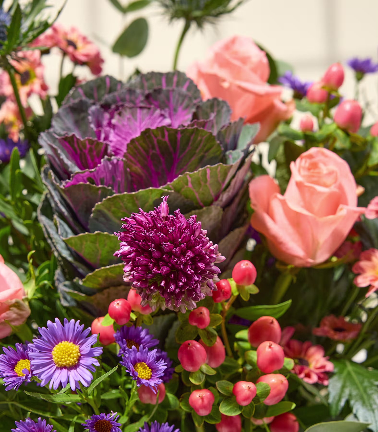 Ein farbenprächtiger Blumenstrauß, in dessen Vordergrund ein auffälliger violetter Zierkohl zu sehen ist, hebt sich von einem weichen, verschwommenen Hintergrund ab. (Beschreibungstext KI-generiert)