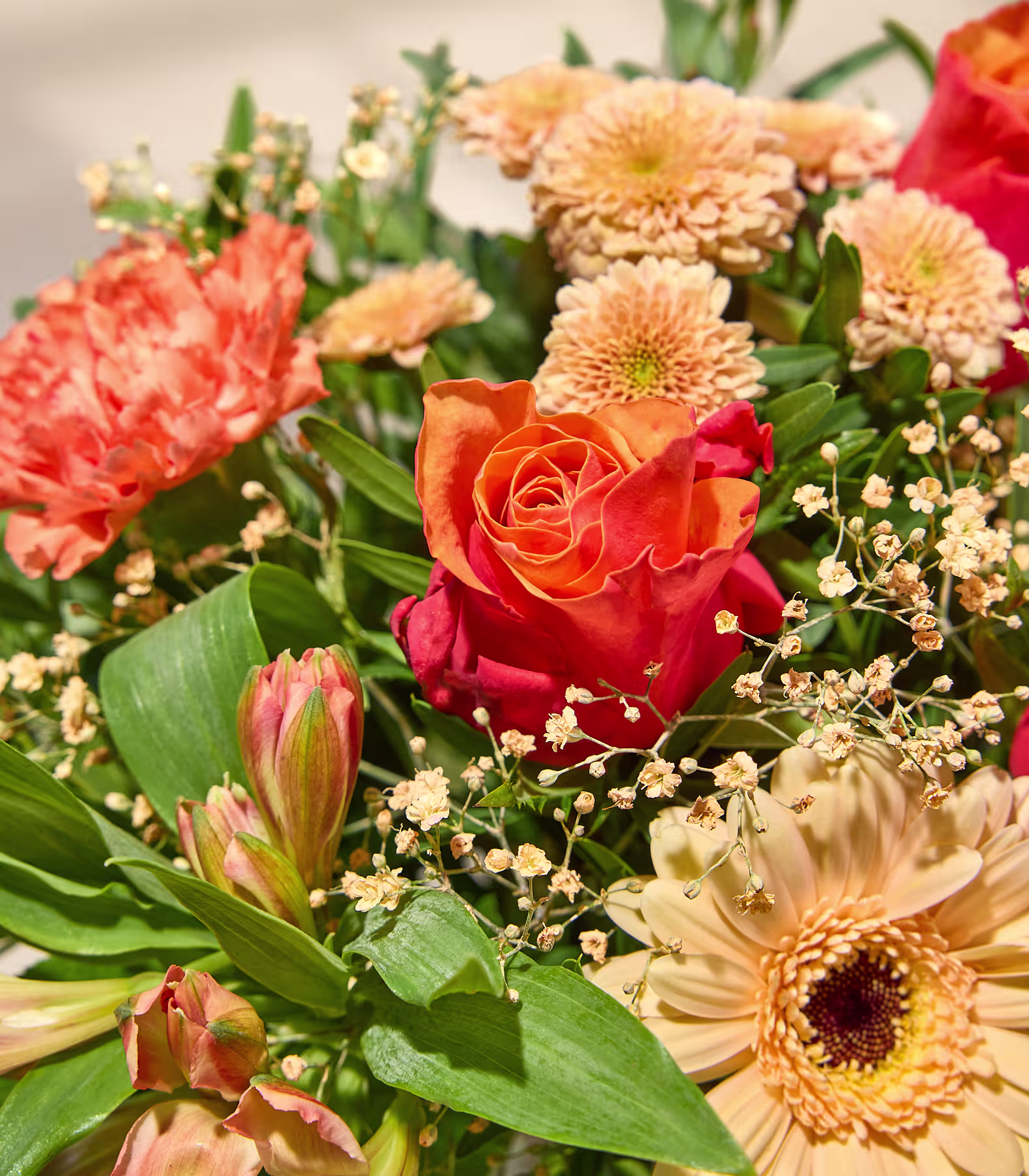 Ein leuchtender Blumenstrauß aus orangefarbenen und pfirsichfarbenen Blüten, darunter Rosen, Nelken und Gerbera, hebt sich von einem sanft verschwommenen, hellen Hintergrund ab. (Beschreibungstext KI-generiert)