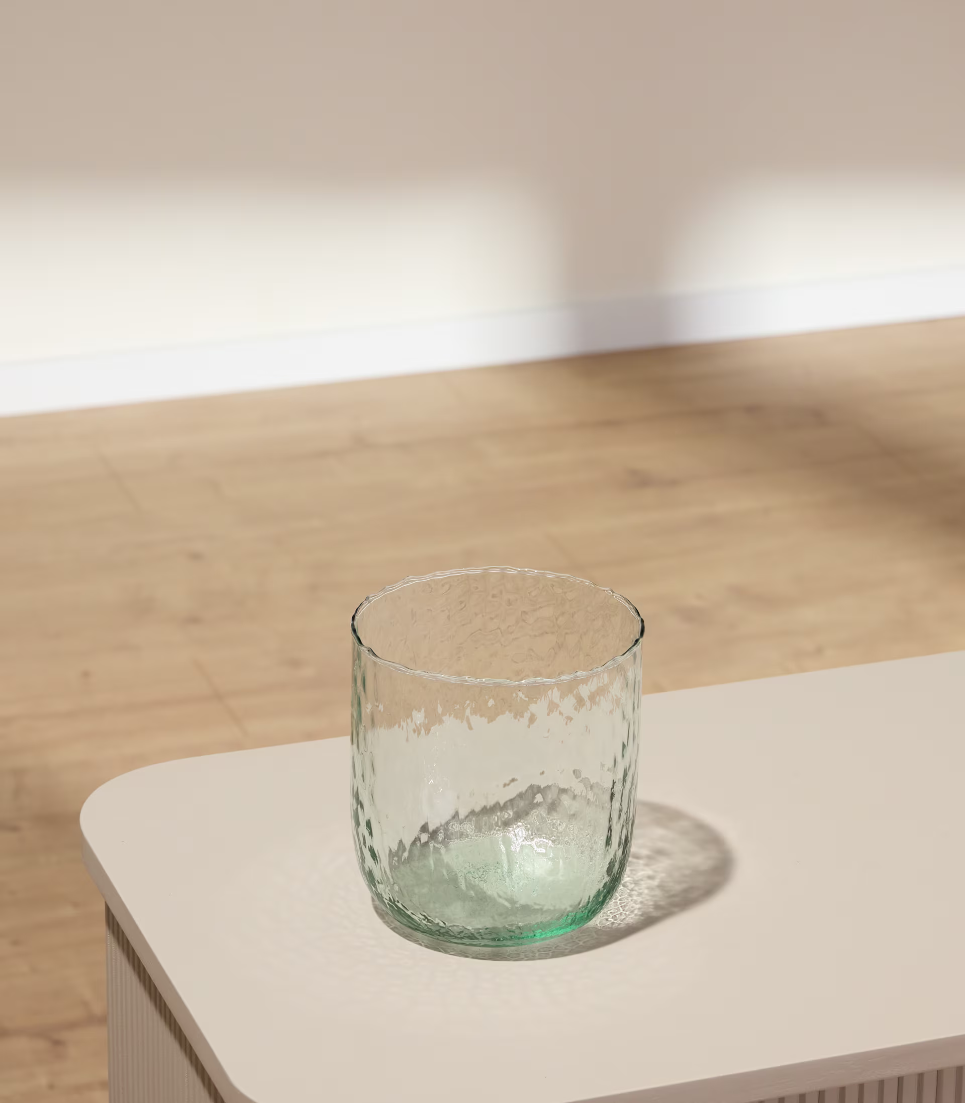 Auf einem hellen Tisch vor einer Wand mit sanften Schatten steht eine strukturierte Glasplatte. (Beschreibungstext KI-generiert)