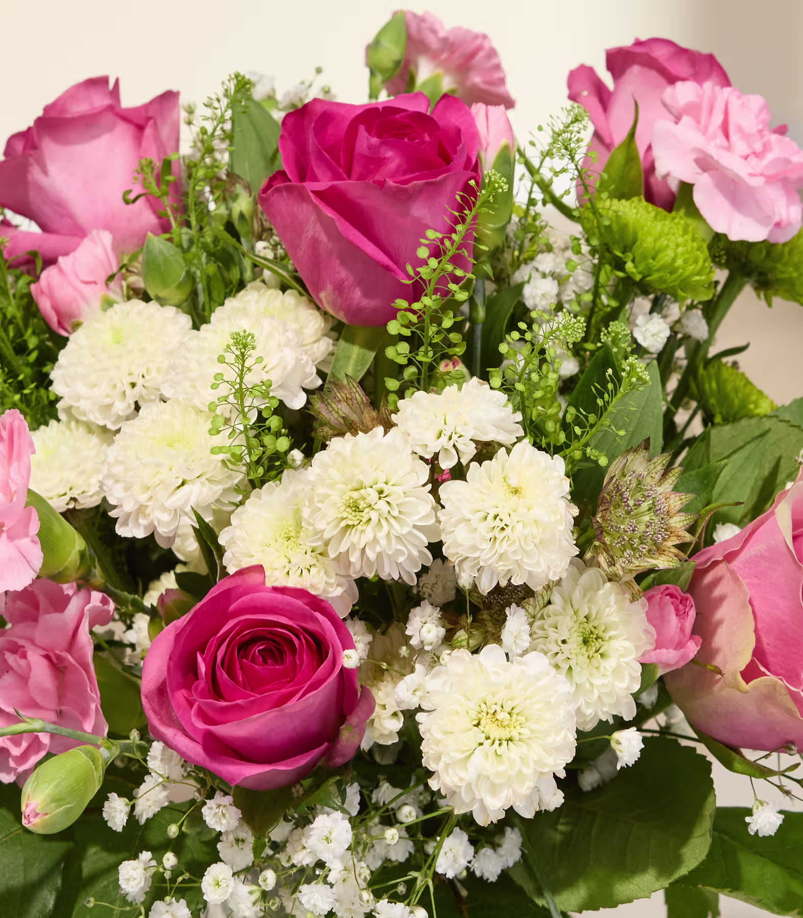 Ein leuchtender Strauß aus rosa Rosen und weißen Chrysanthemen füllt den Vordergrund vor einem schlichten, hellen Hintergrund. (Beschreibungstext KI-generiert)