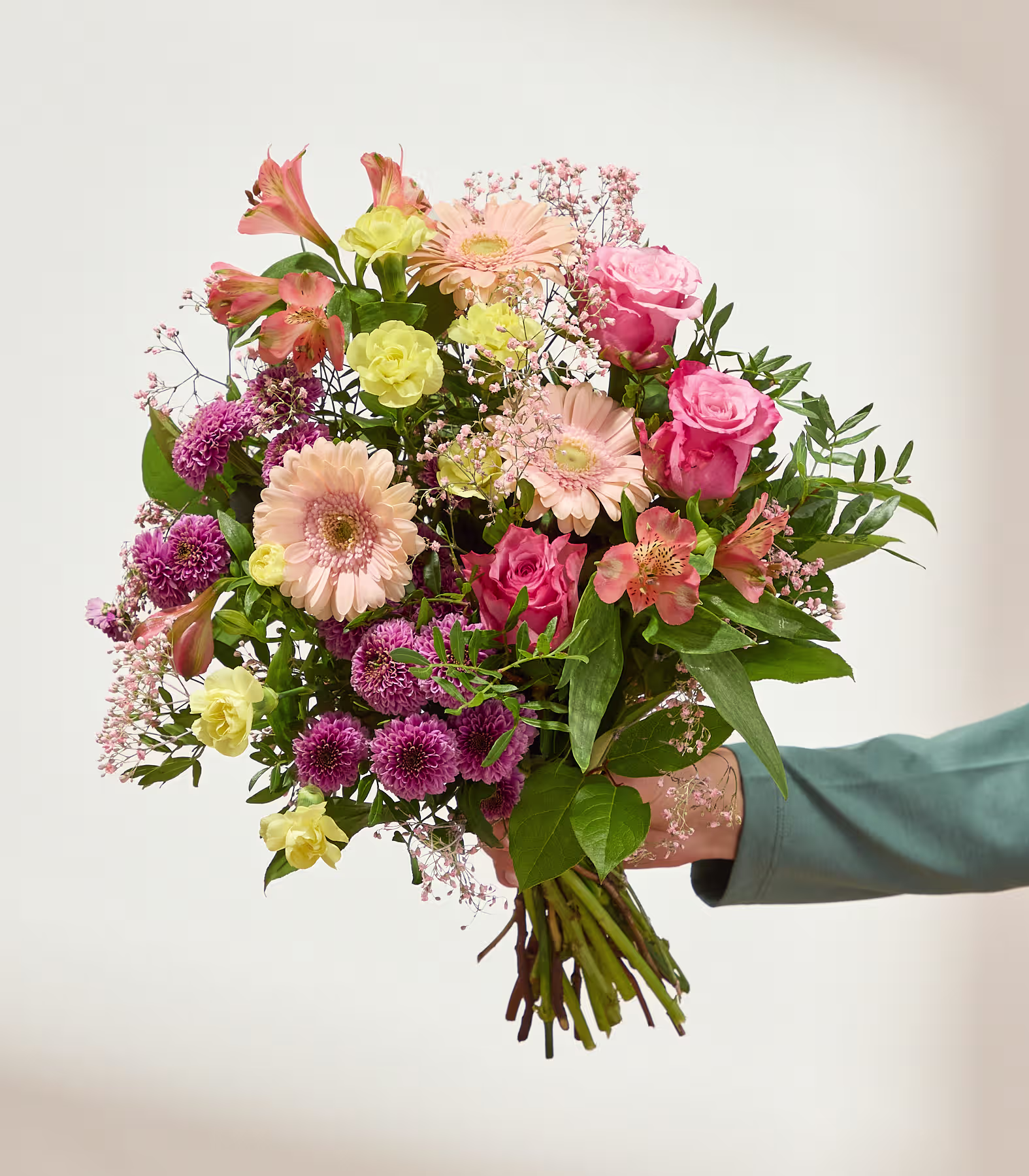 Ein farbenfroher Strauß aus rosa, gelben und pfirsichfarbenen Blumen hebt sich von einem schlichten, hellen Hintergrund ab. (Beschreibungstext KI-generiert)