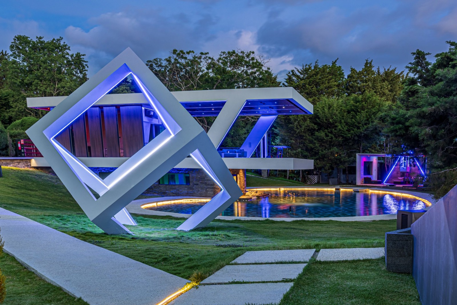 Illuminated geometric led sculpture beside a pool at a modern villa during twilight.