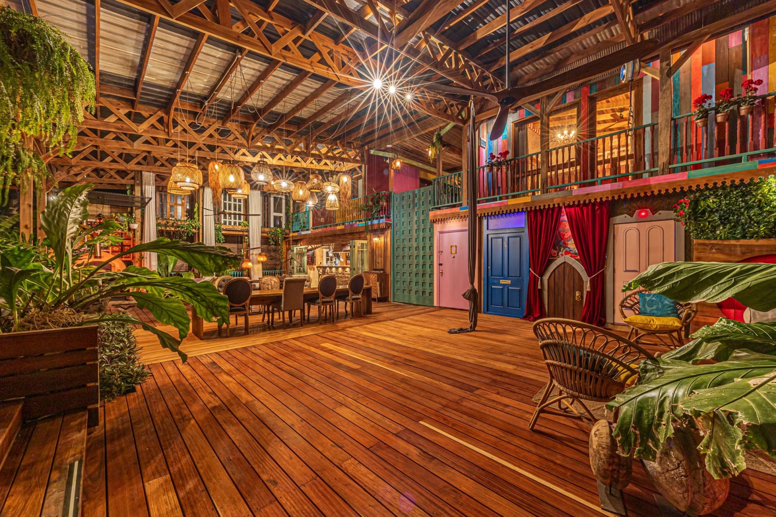 Covered wooden lounge with tropical plants and colorful boho-style doors.