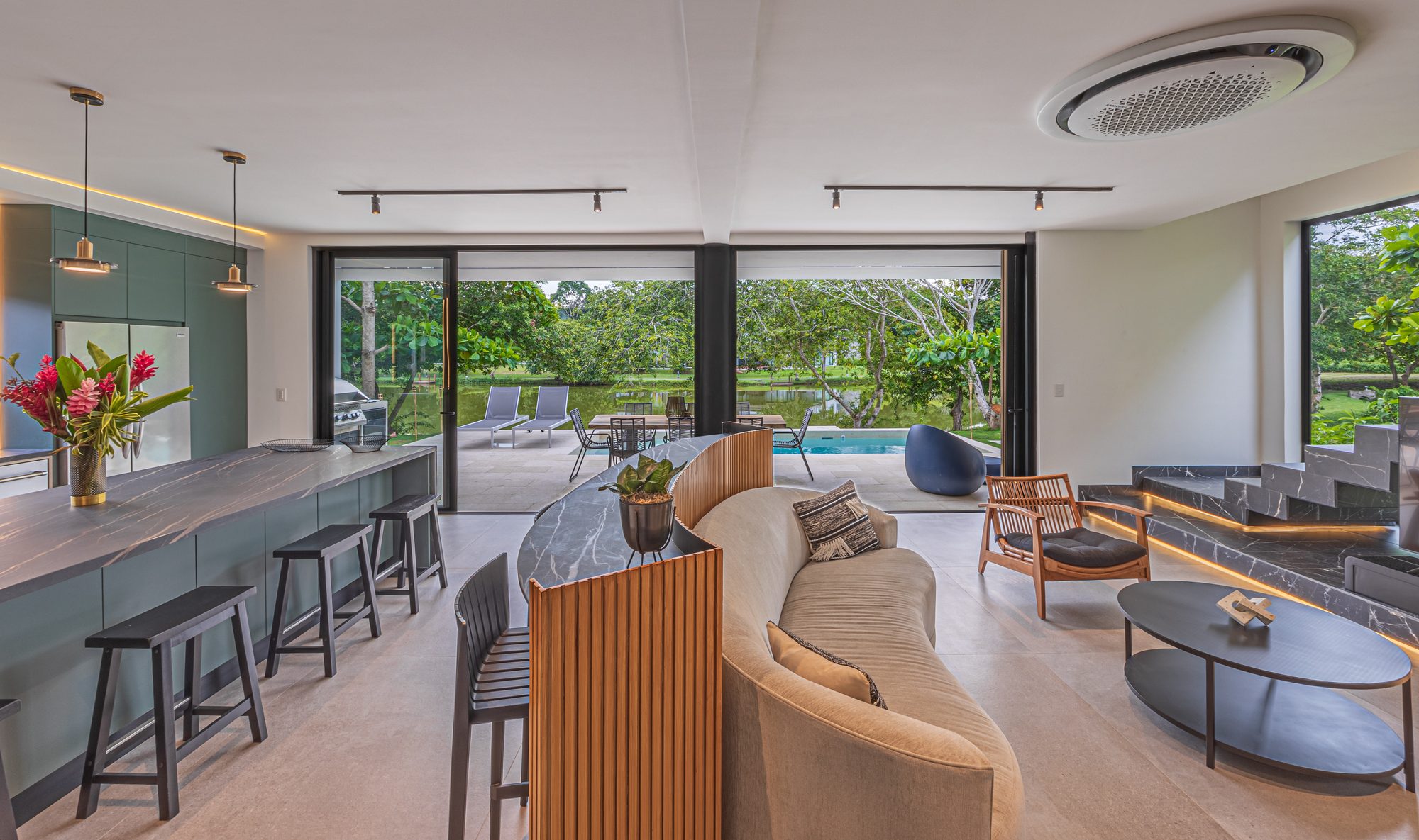 Open-plan living and kitchen area with view to pool and garden.