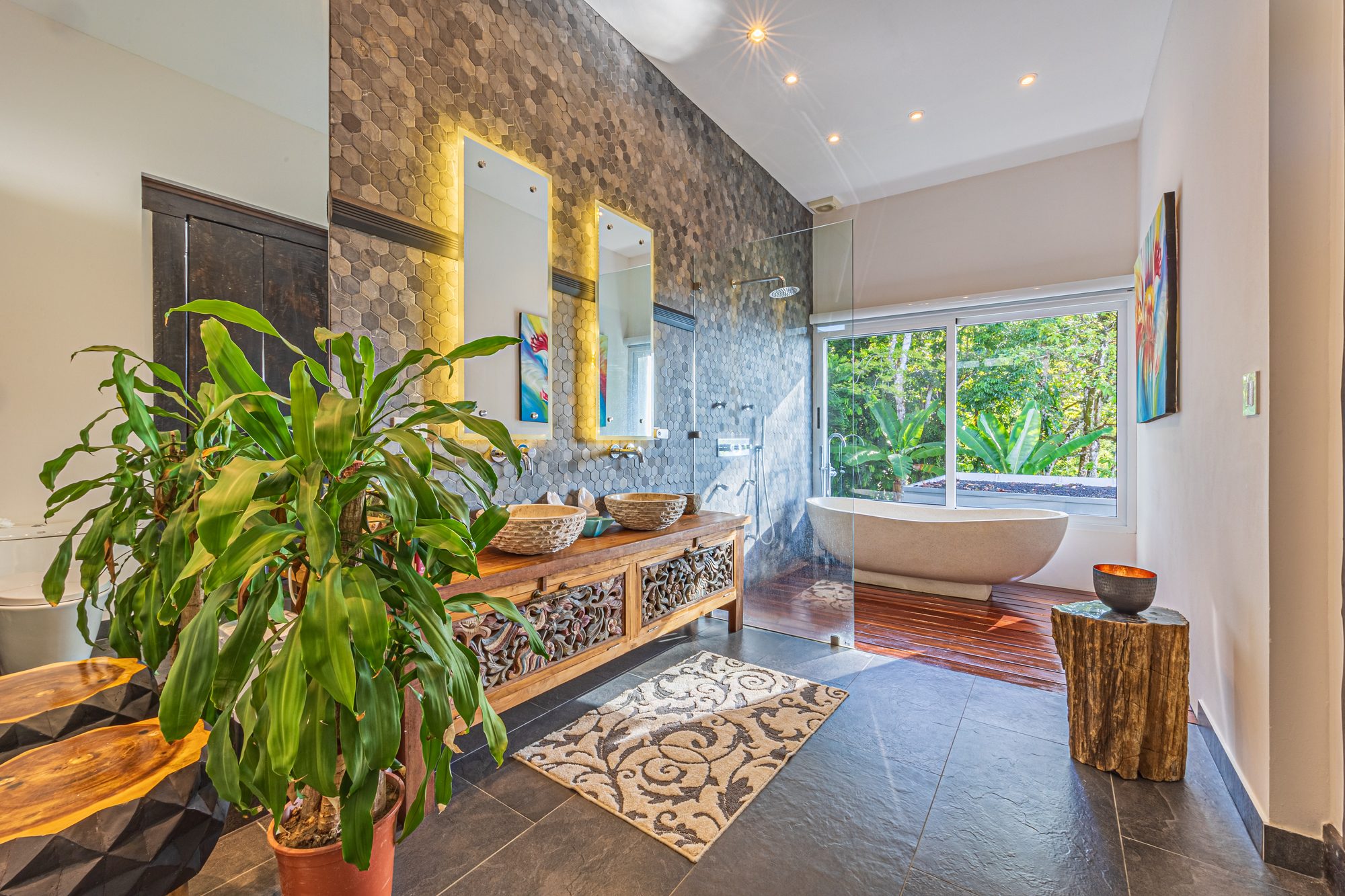 Luxury bathroom with freestanding tub facing a jungle-view window.
