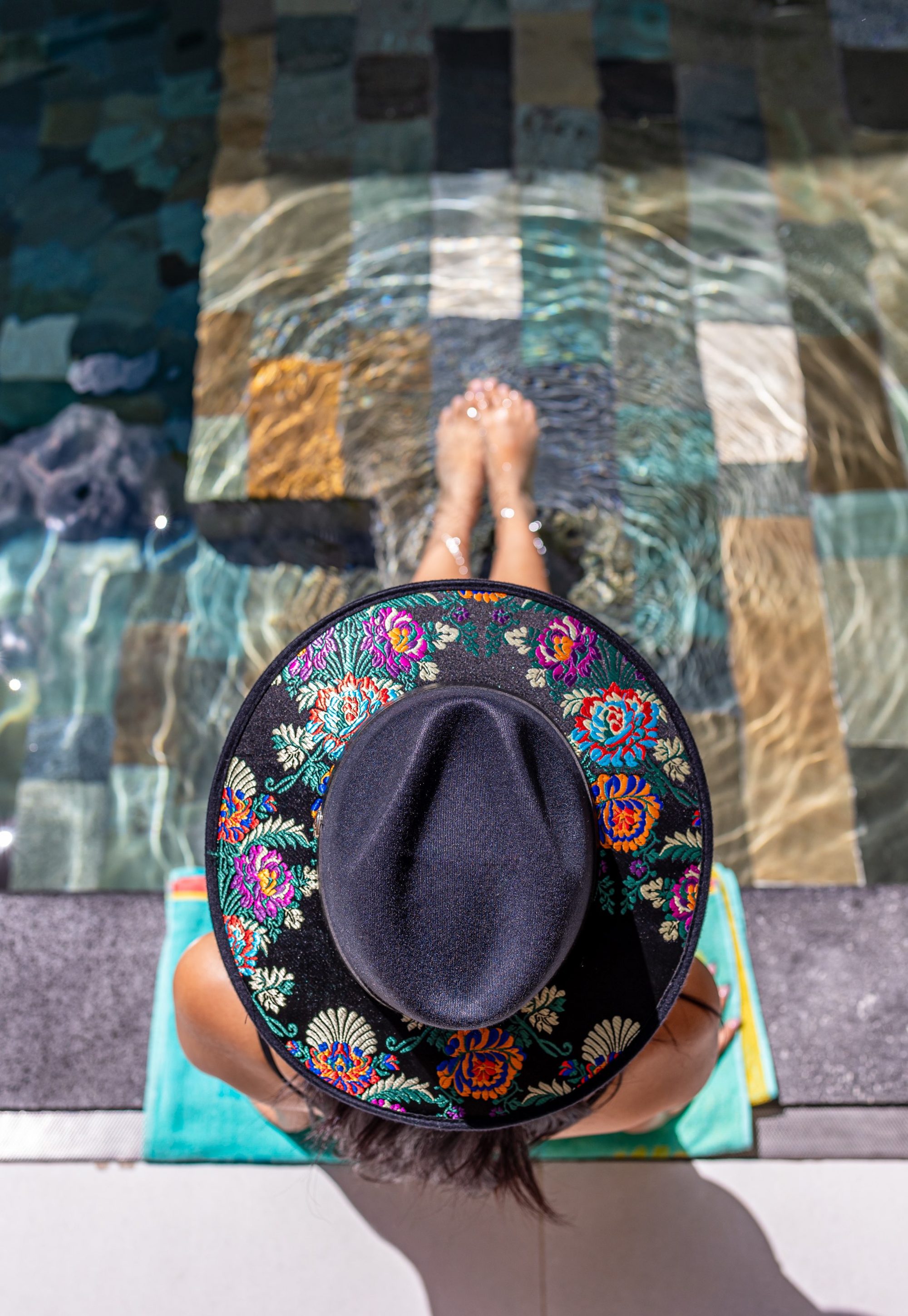 Overhead view of a person in a hat relaxing by the pool