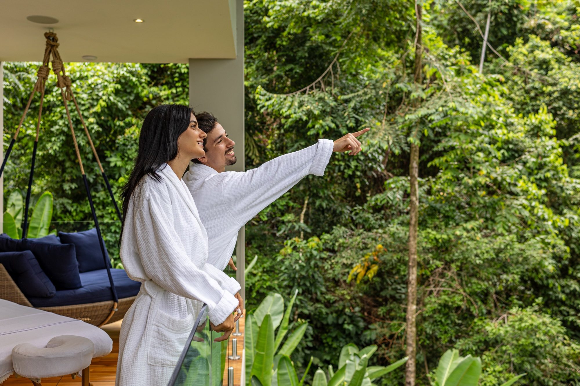 Couple in white robes gazing at the rainforest from a spa balcony