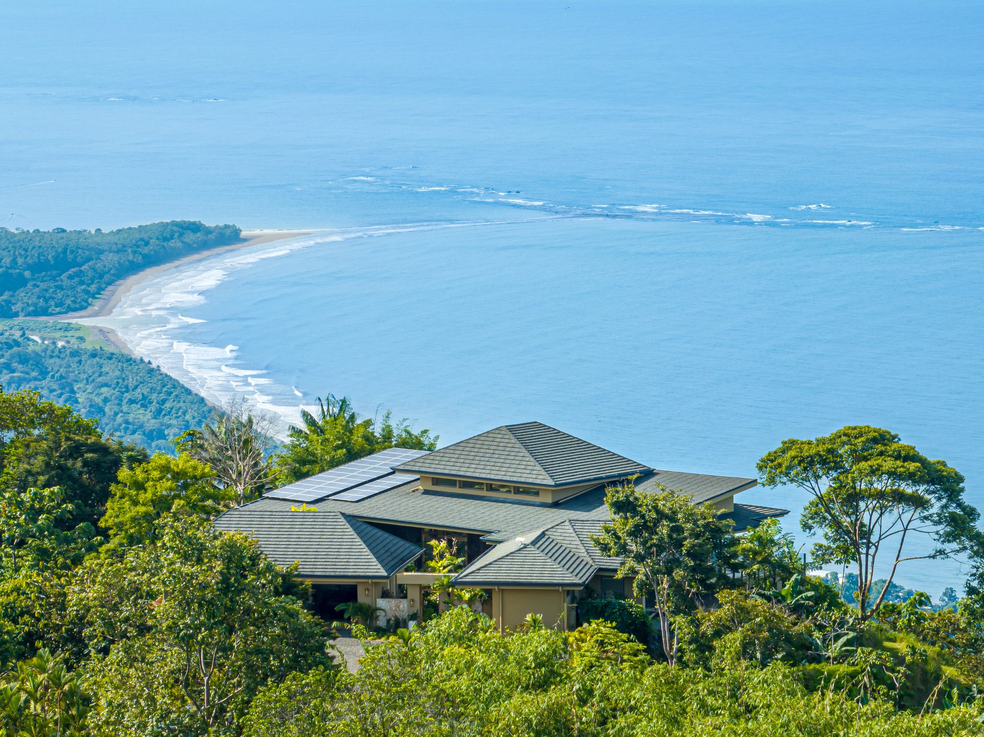 Casa de lujo con techos a cuatro aguas rodeada de selva y vista panorámica al océano