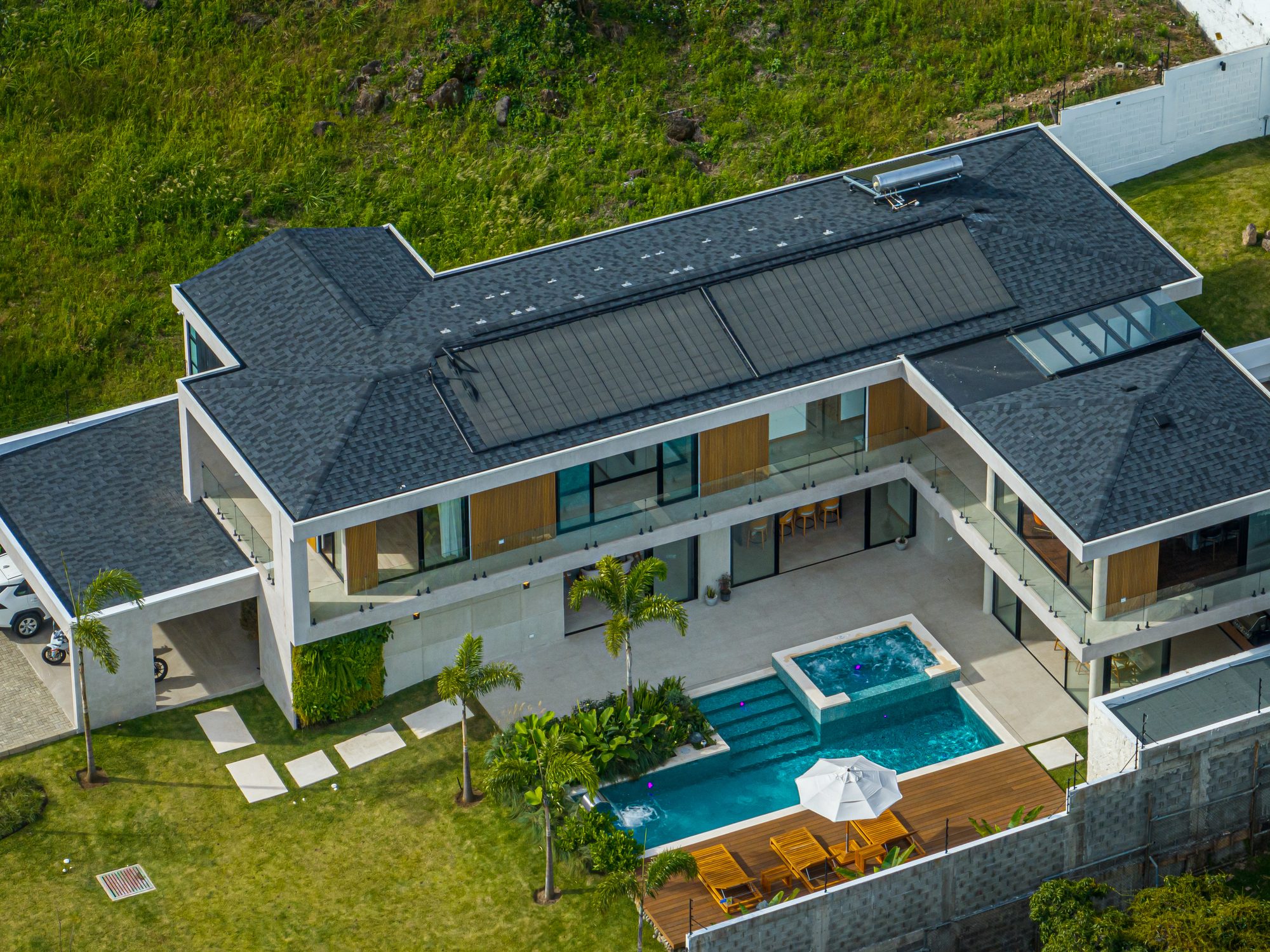 Aerial view of a modern villa with infinity pool and tropical garden.