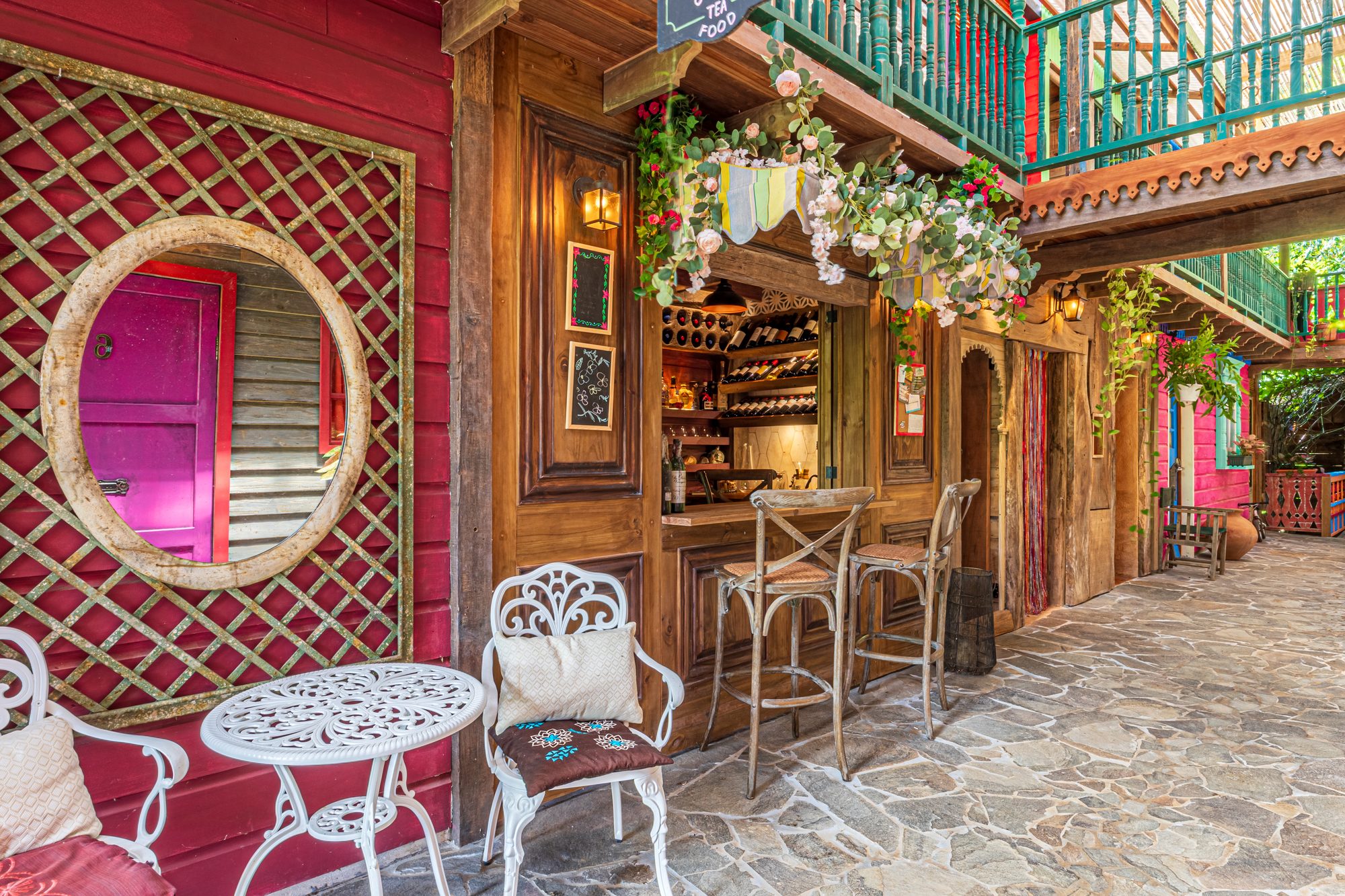 Rustic outdoor bar with wine racks and colorful terrace with wrought iron tables