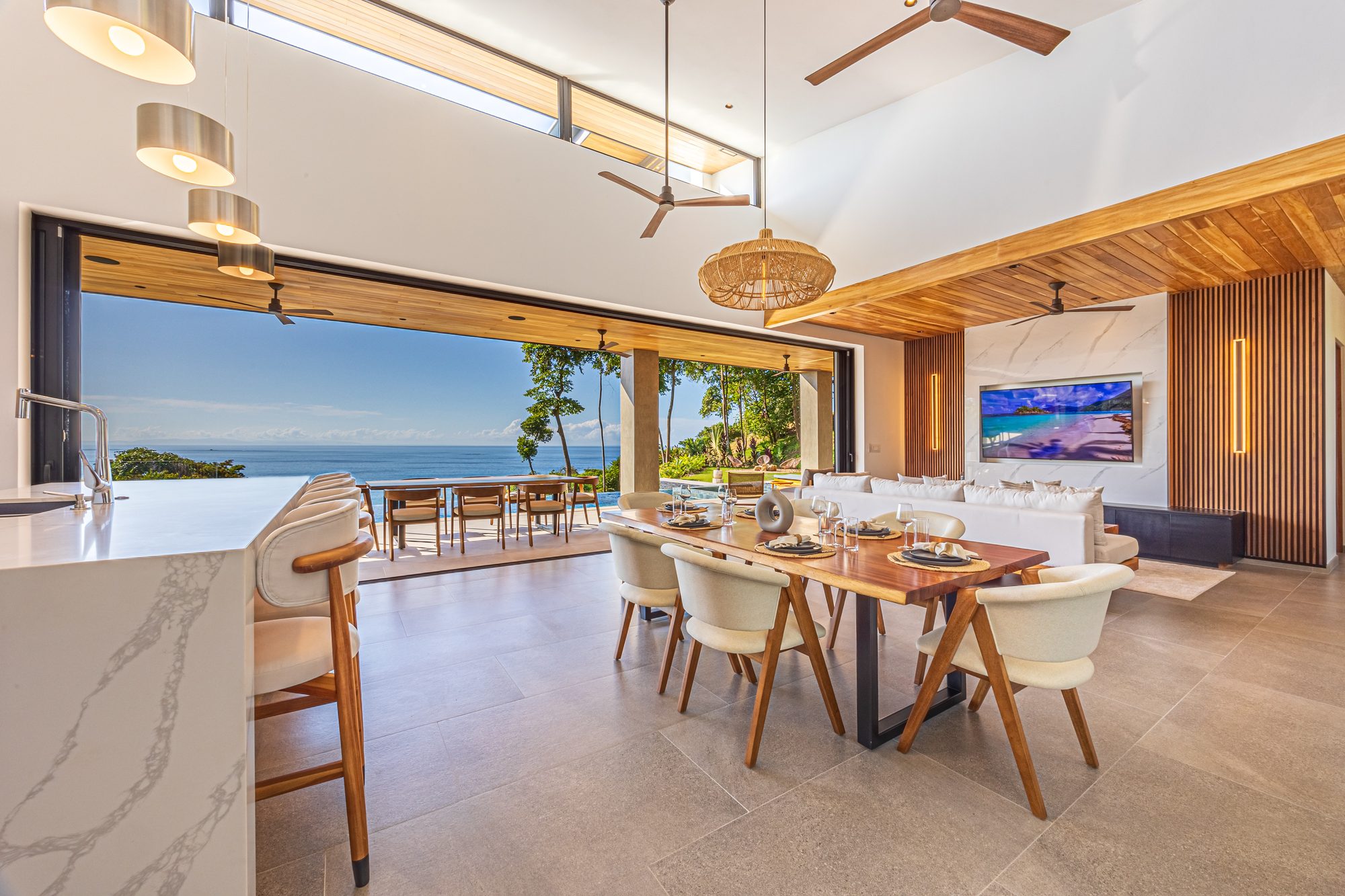 Open-concept living and dining area with ocean views and tall wood ceilings.