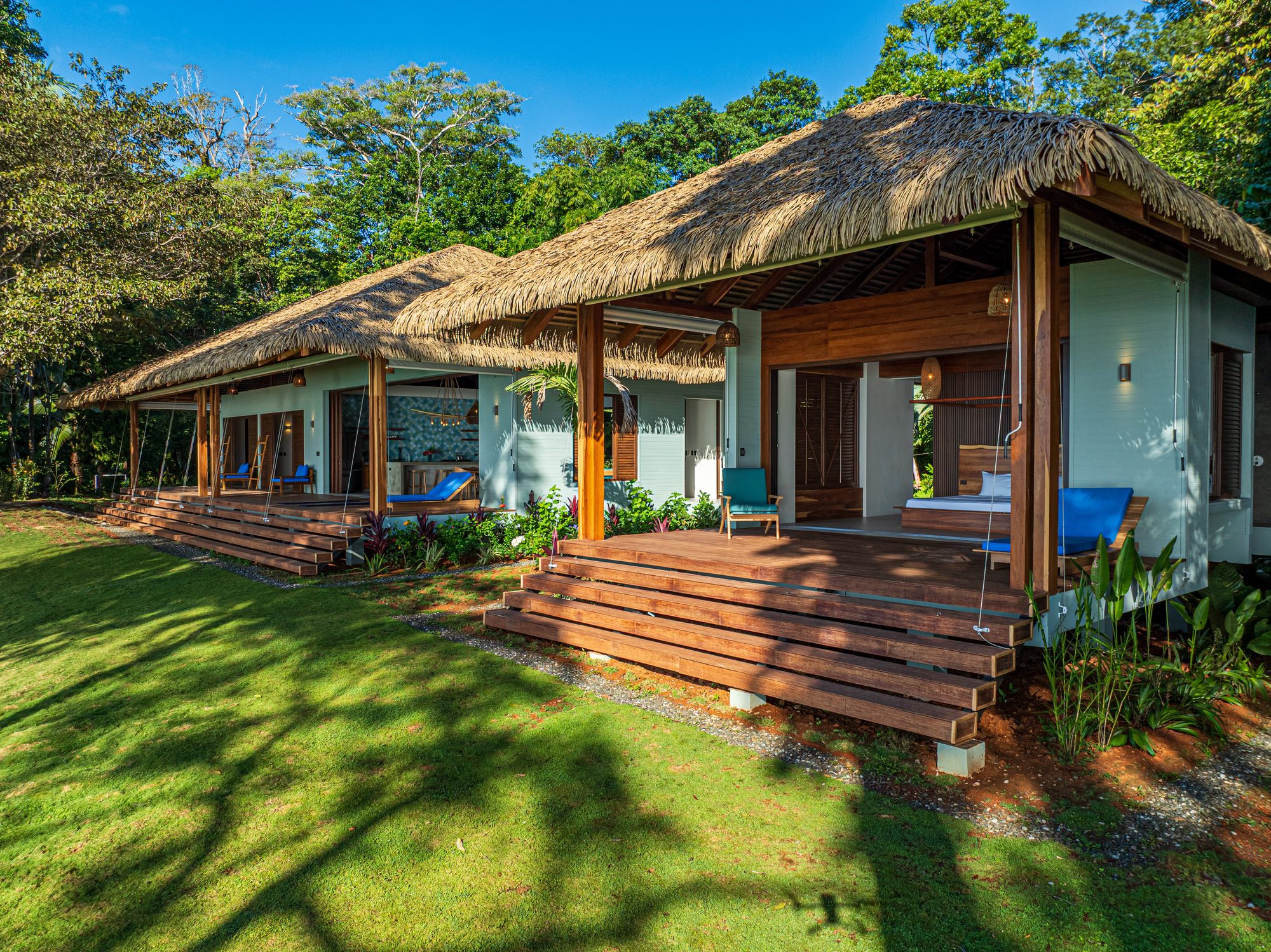Luxury bungalow with thatched roof surrounded by tropical jungle and garden.
