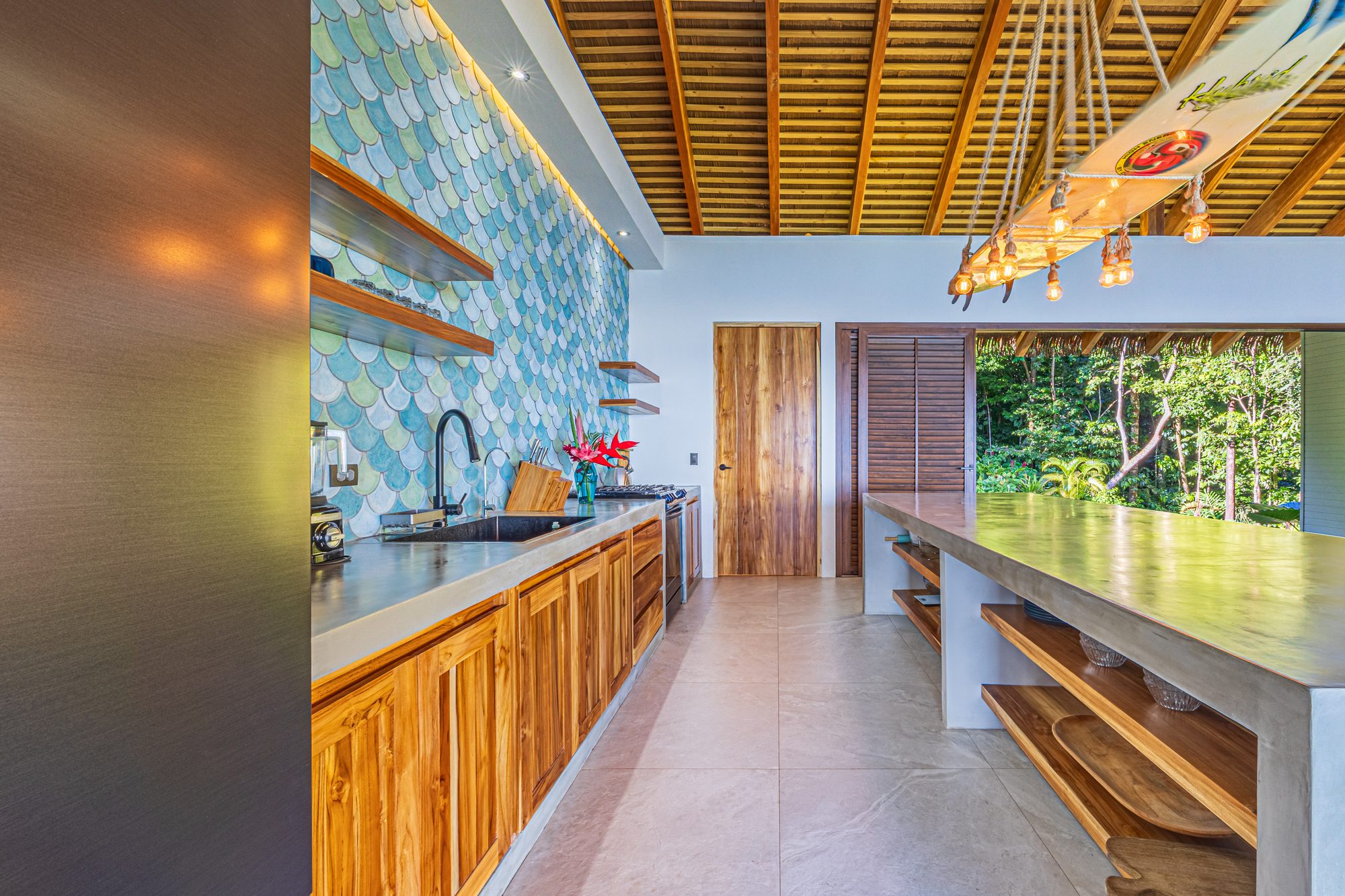 Designer kitchen with fish-scale tile backsplash and jungle view.
