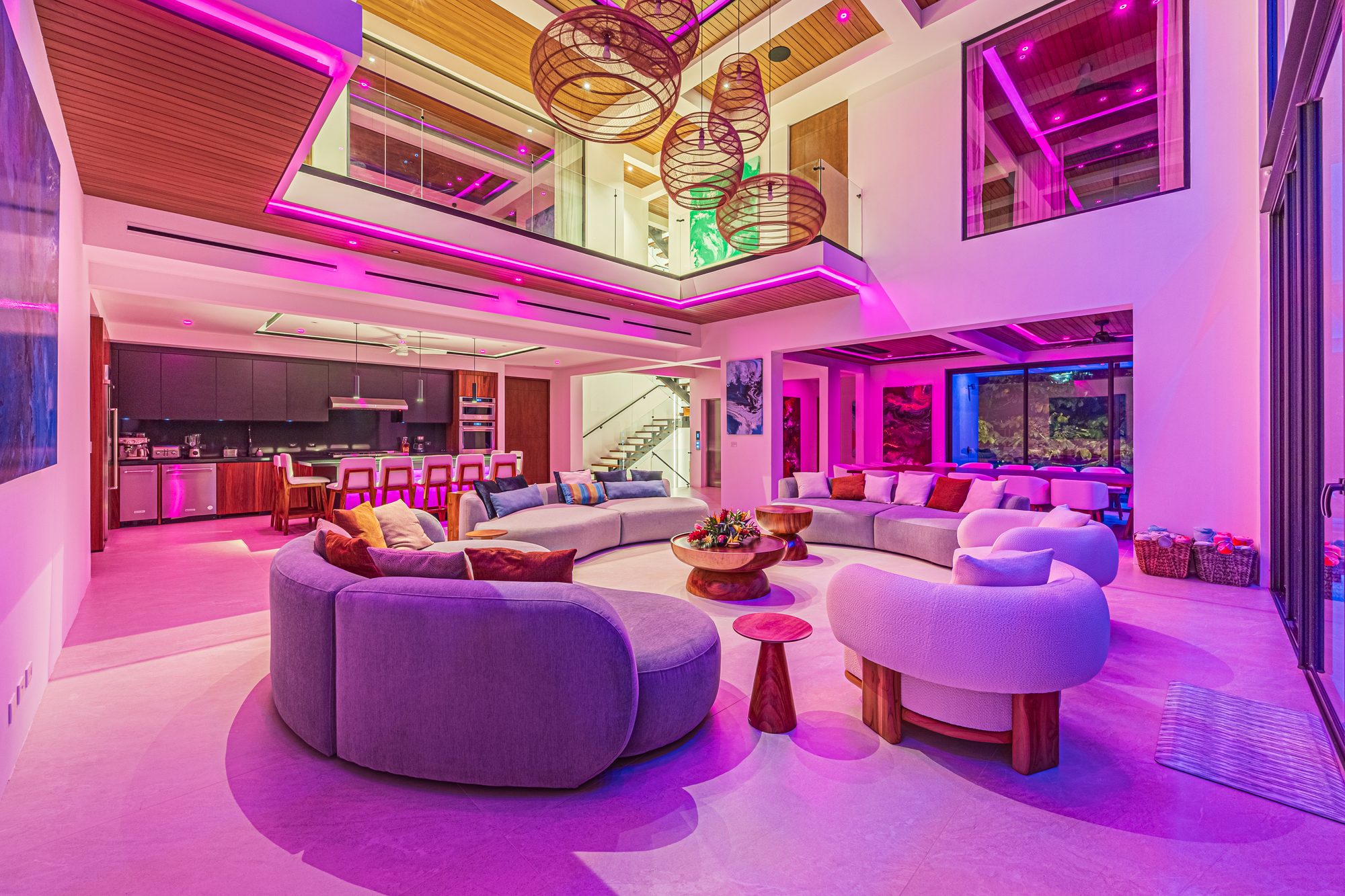 Double-height living room with pink LED lighting and modern circular sofas.