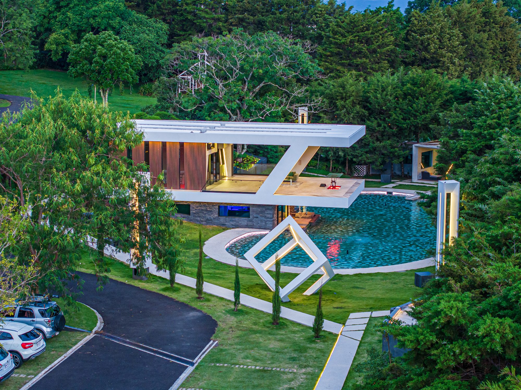 Aerial view of modern villa with circular pool surrounded by tropical garden.