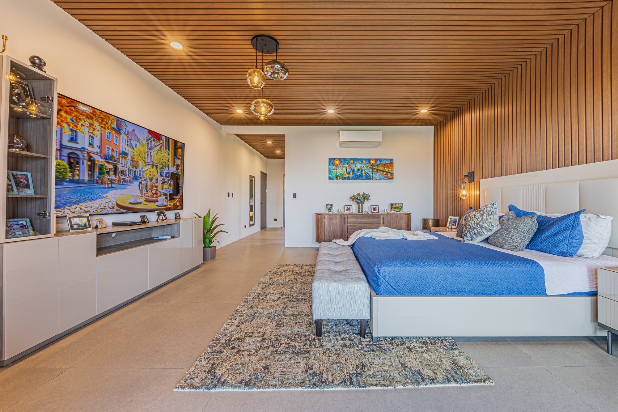 Master bedroom with wood-slat ceiling and blue bedding.