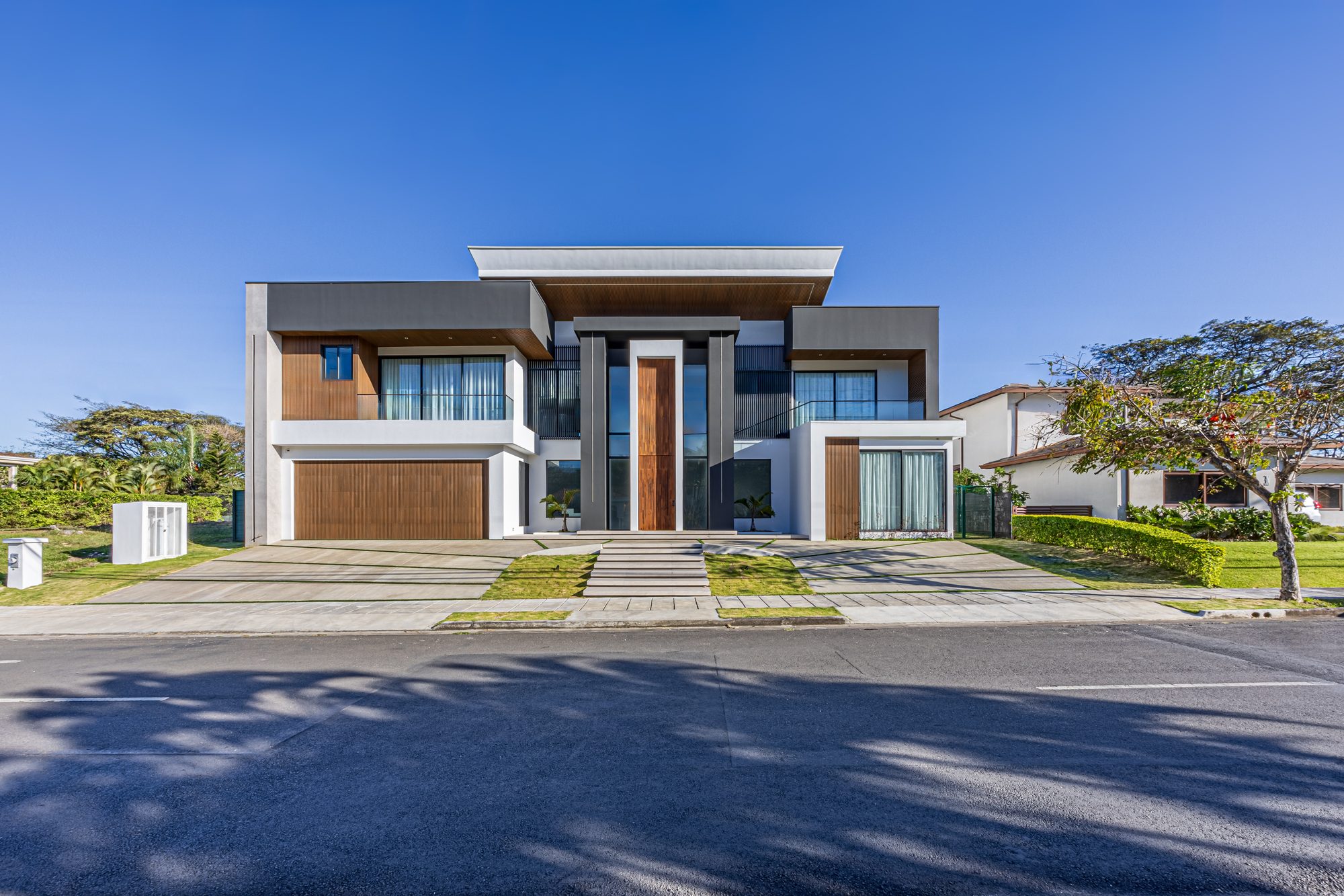 Front facade of a modern two-story house with wood and concrete finishes.