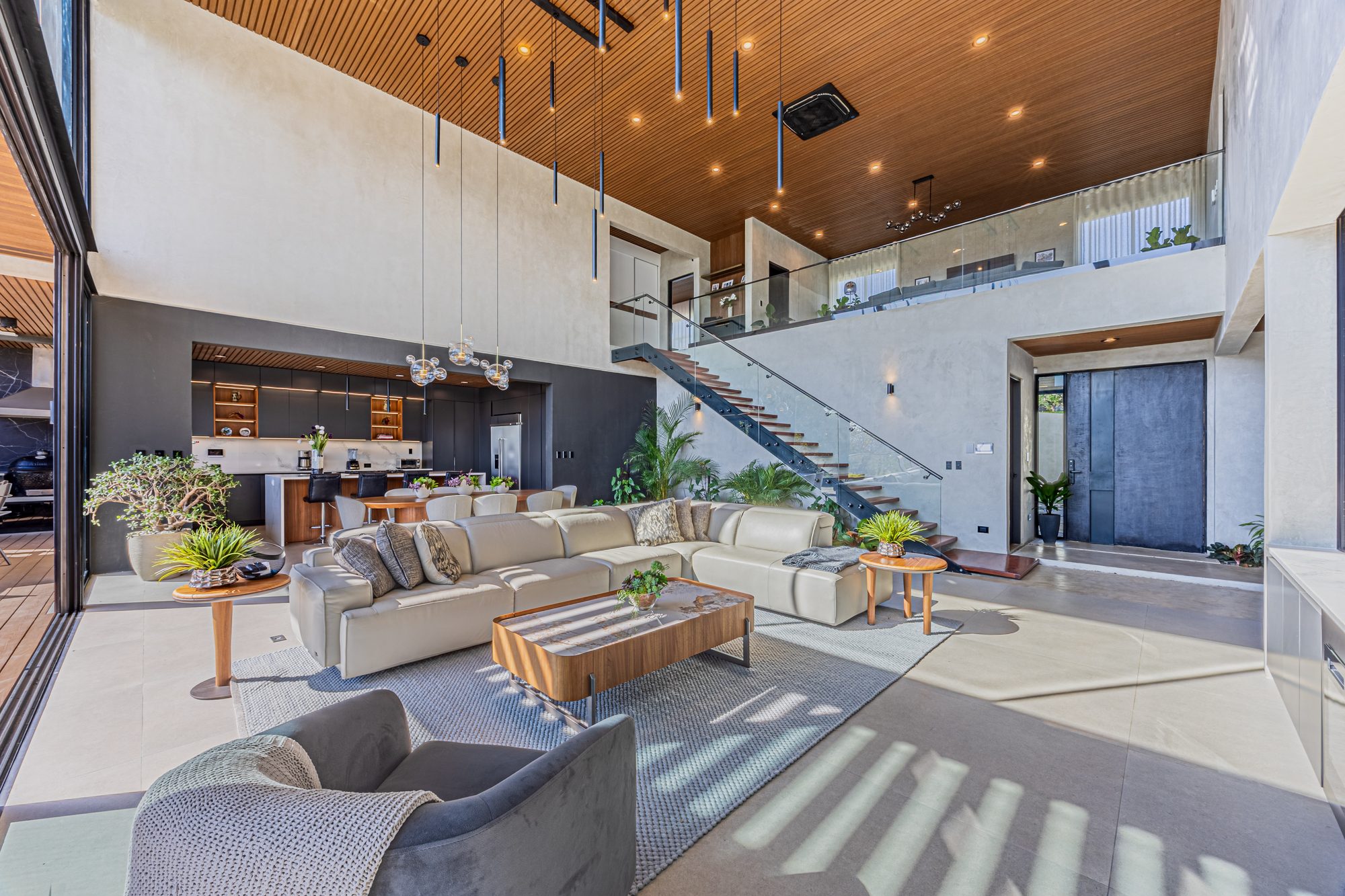 Double-height living room with floating staircase and integrated modern kitchen.