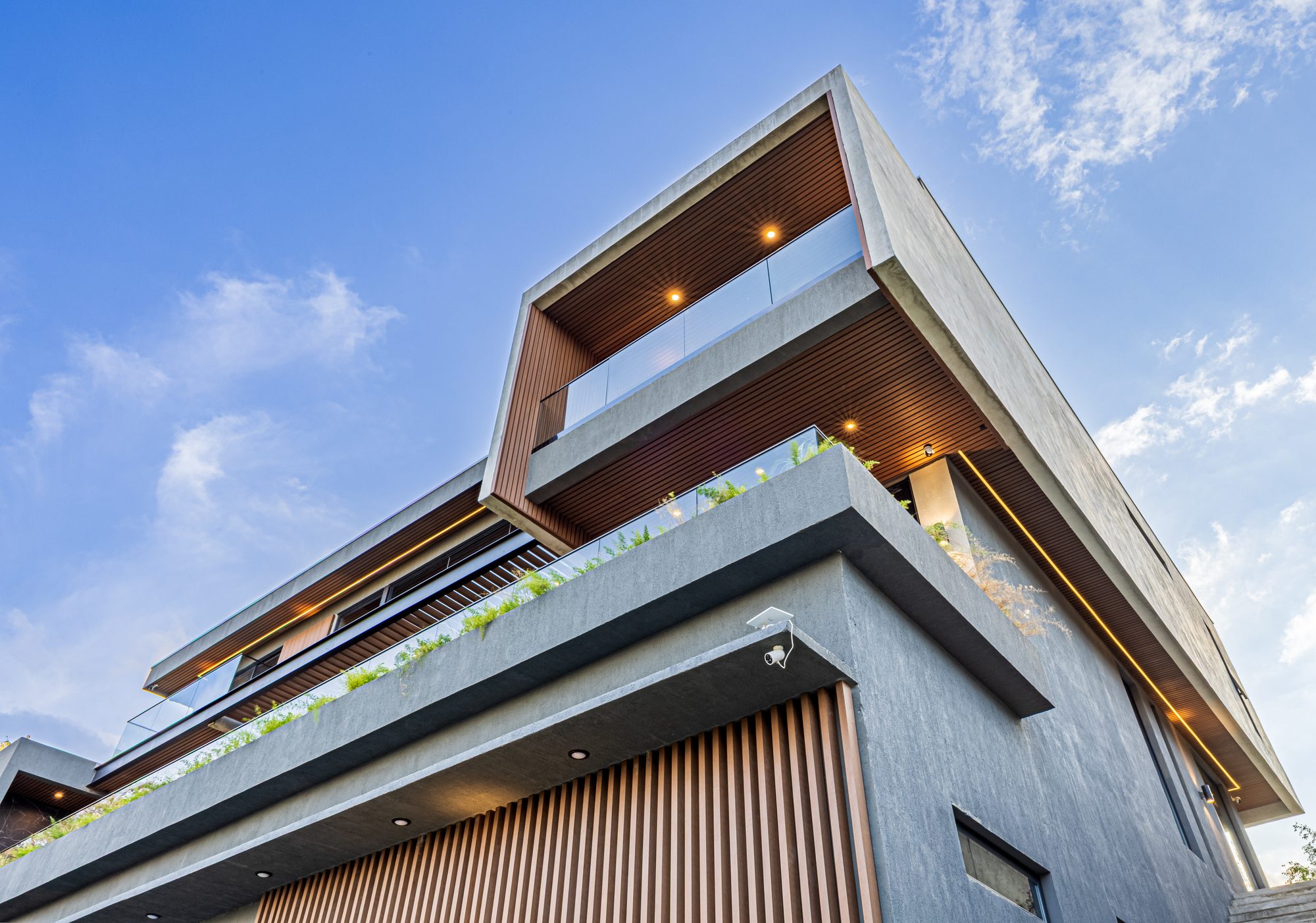 Angled view of a modern concrete facade with wood accents and cantilevered balconies.
