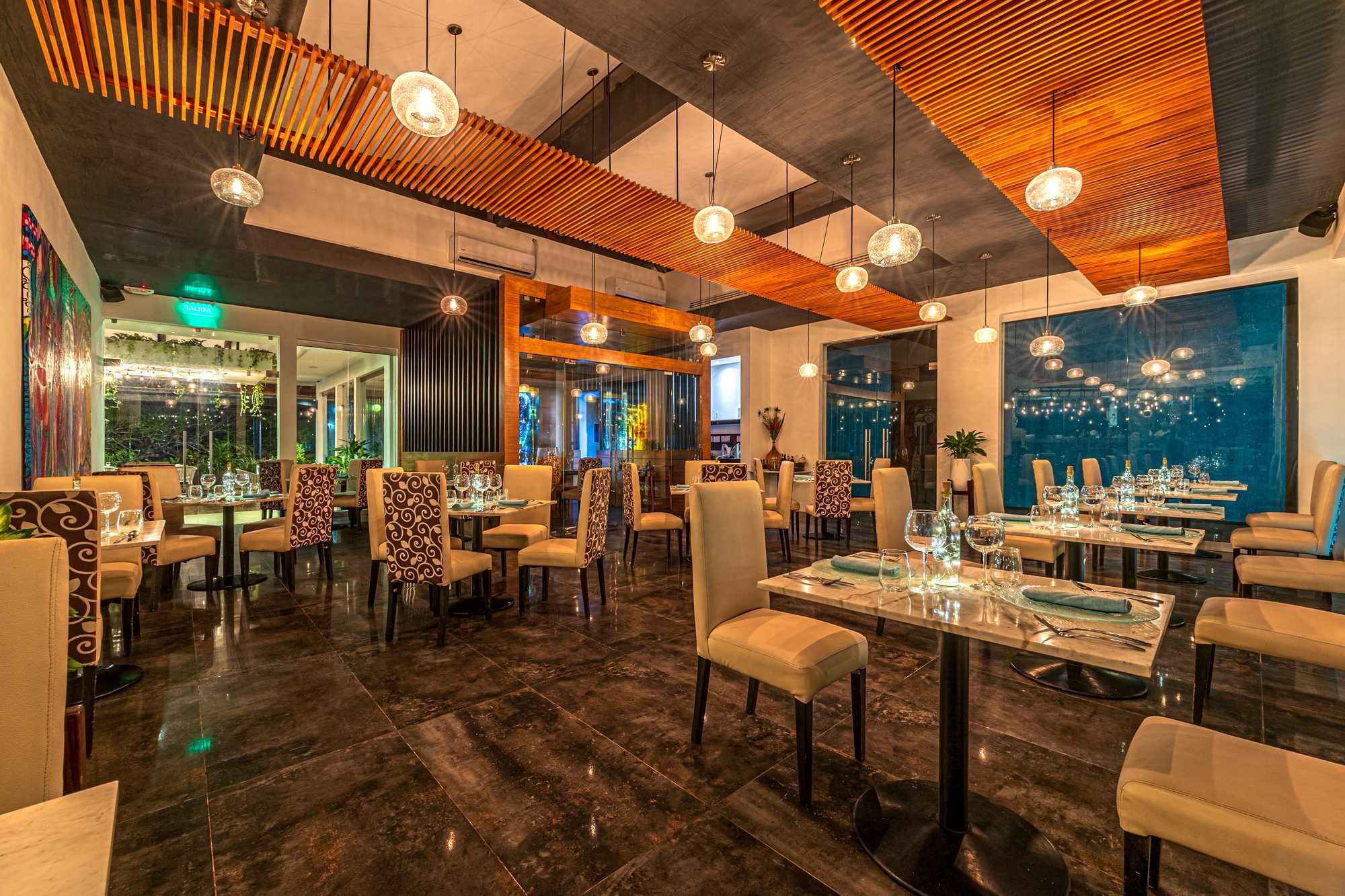 Elegant restaurant with wood-slat ceiling and hanging glass pendant lights.