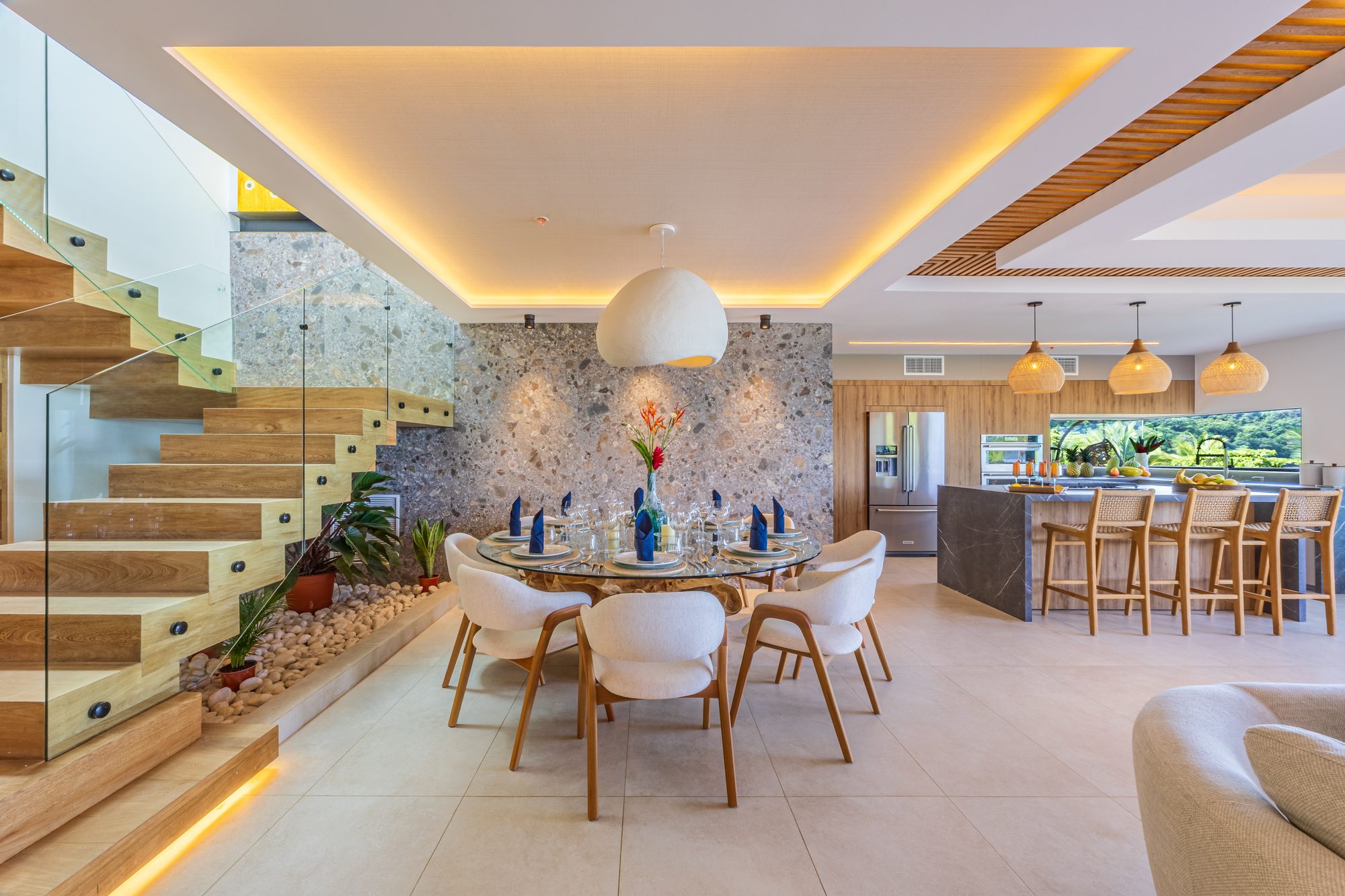 Open-concept dining and kitchen area with wood staircase and nature view