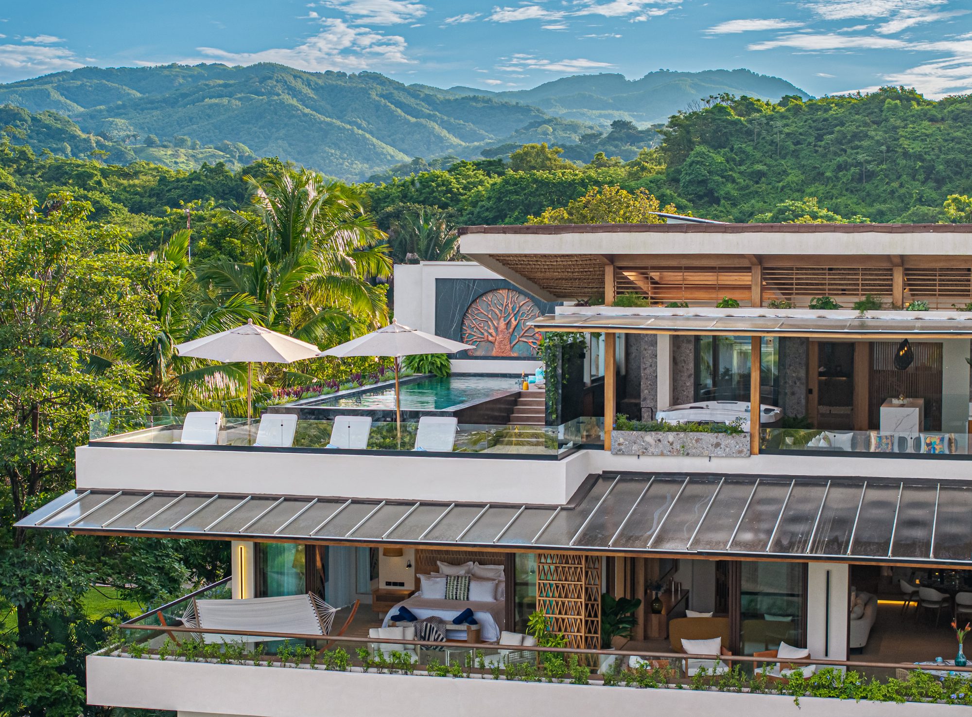 General view of a luxury villa with infinity pool surrounded by jungle and mountains.