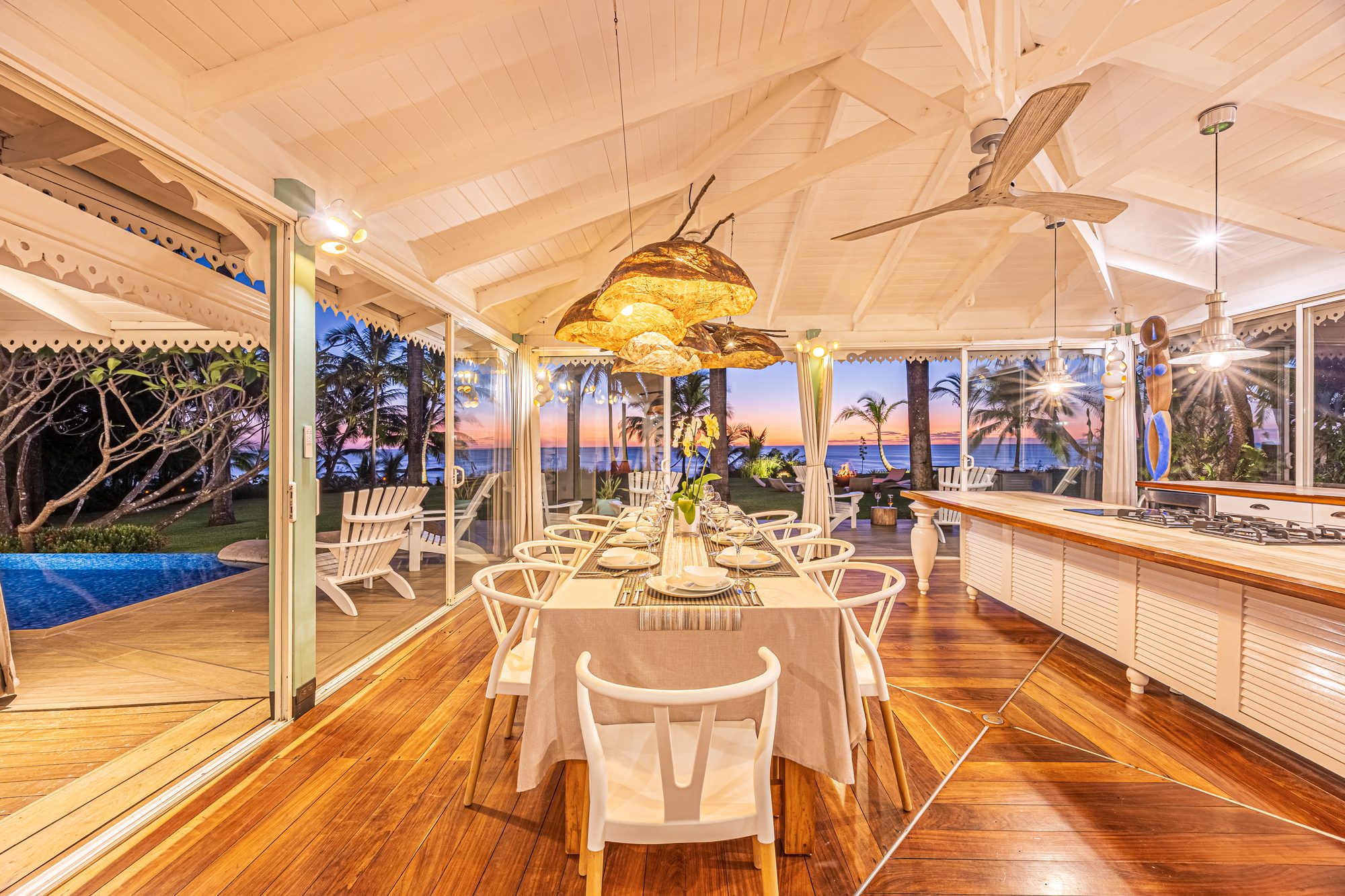 Tropical dining area with sunset ocean view through palm trees