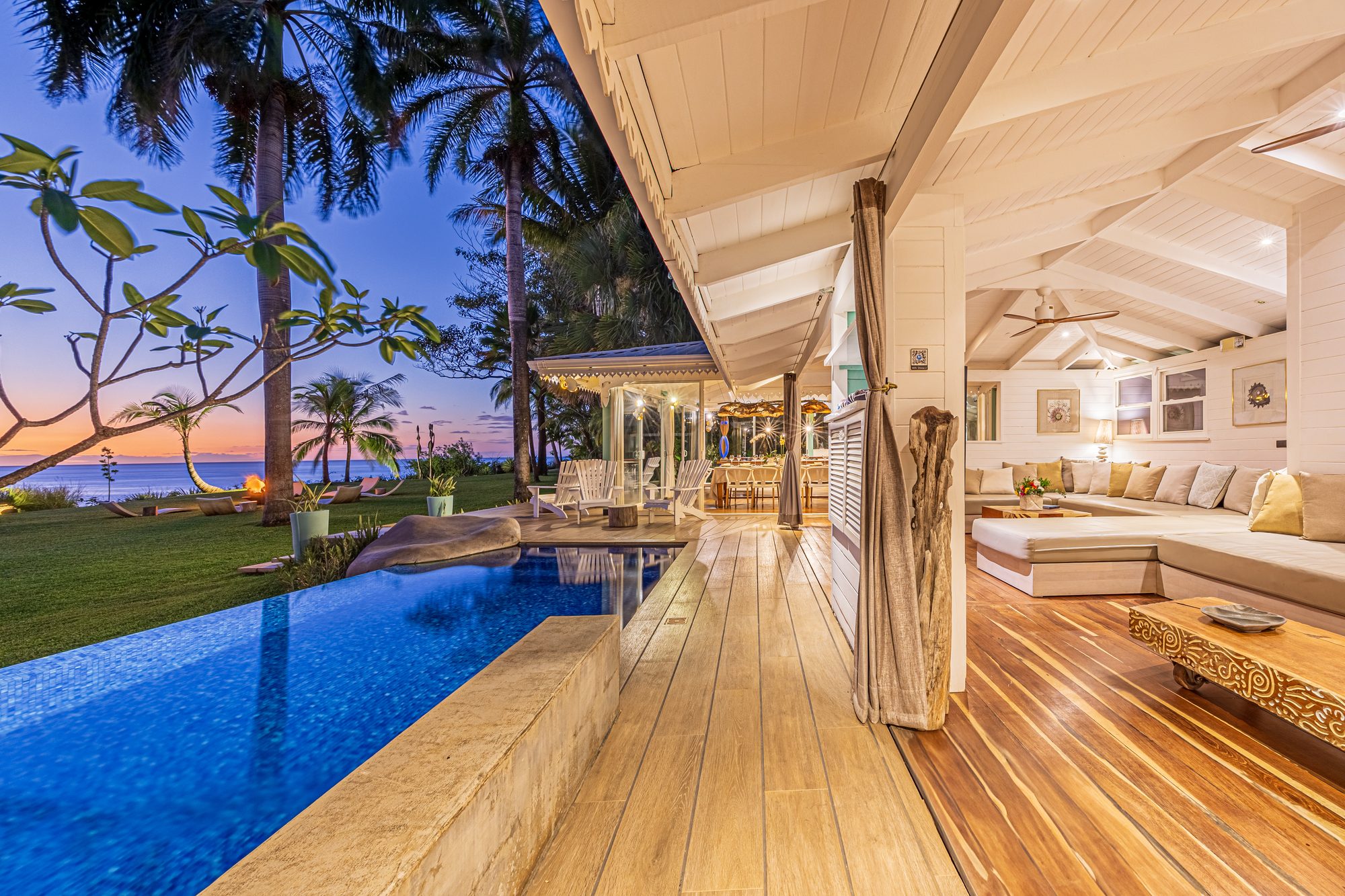 Infinity pool overlooking sunset next to an open-air living room.