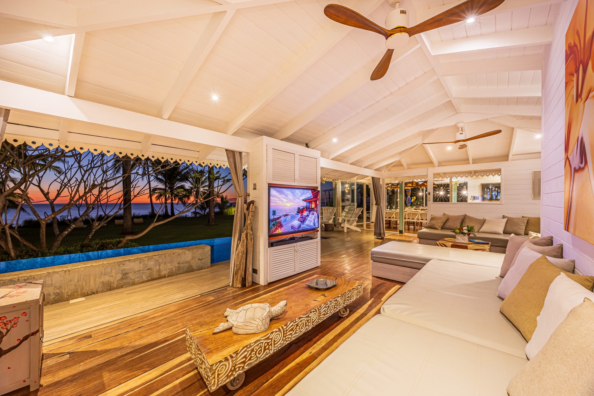 Open-air living room with sunset ocean view and infinity pool.
