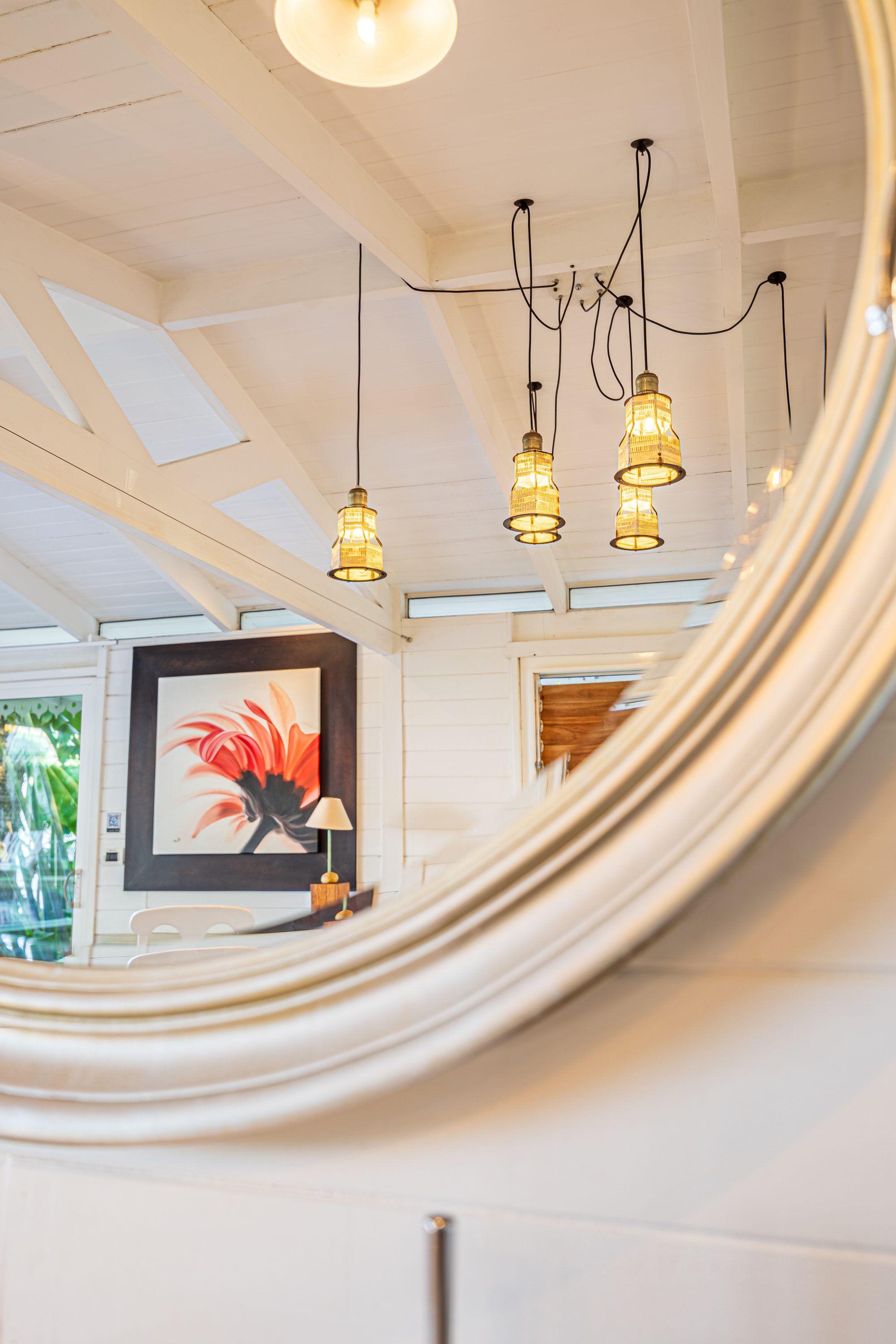 Mirror reflection of bamboo pendant lights under a white wooden ceiling