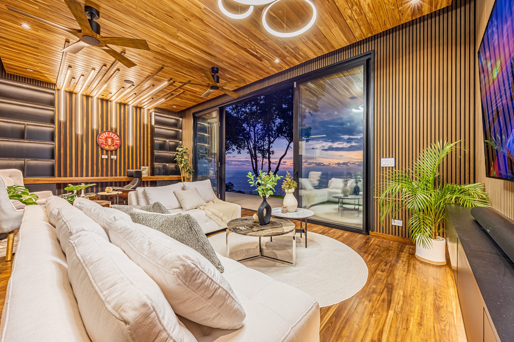 Living room with wood ceiling and sunset ocean view through sliding doors.