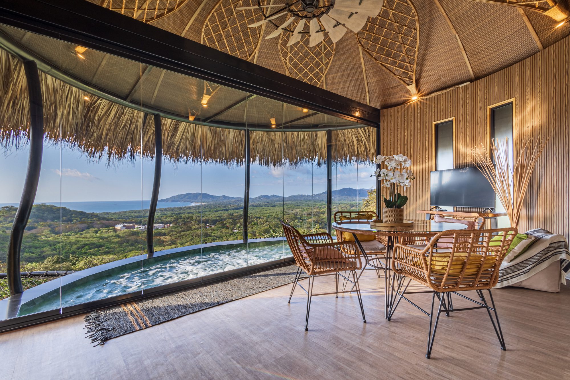 Sala con piscina infinita, techo de palapa y vista panorámica al océano en Costa Rica.