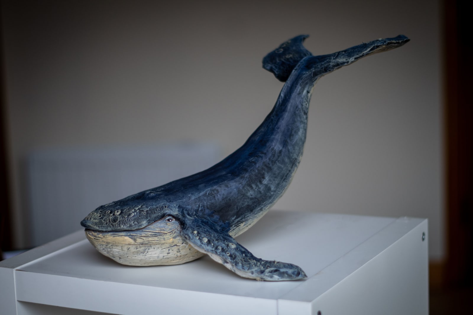 Ceramic whale sculpture on its plinth, full view