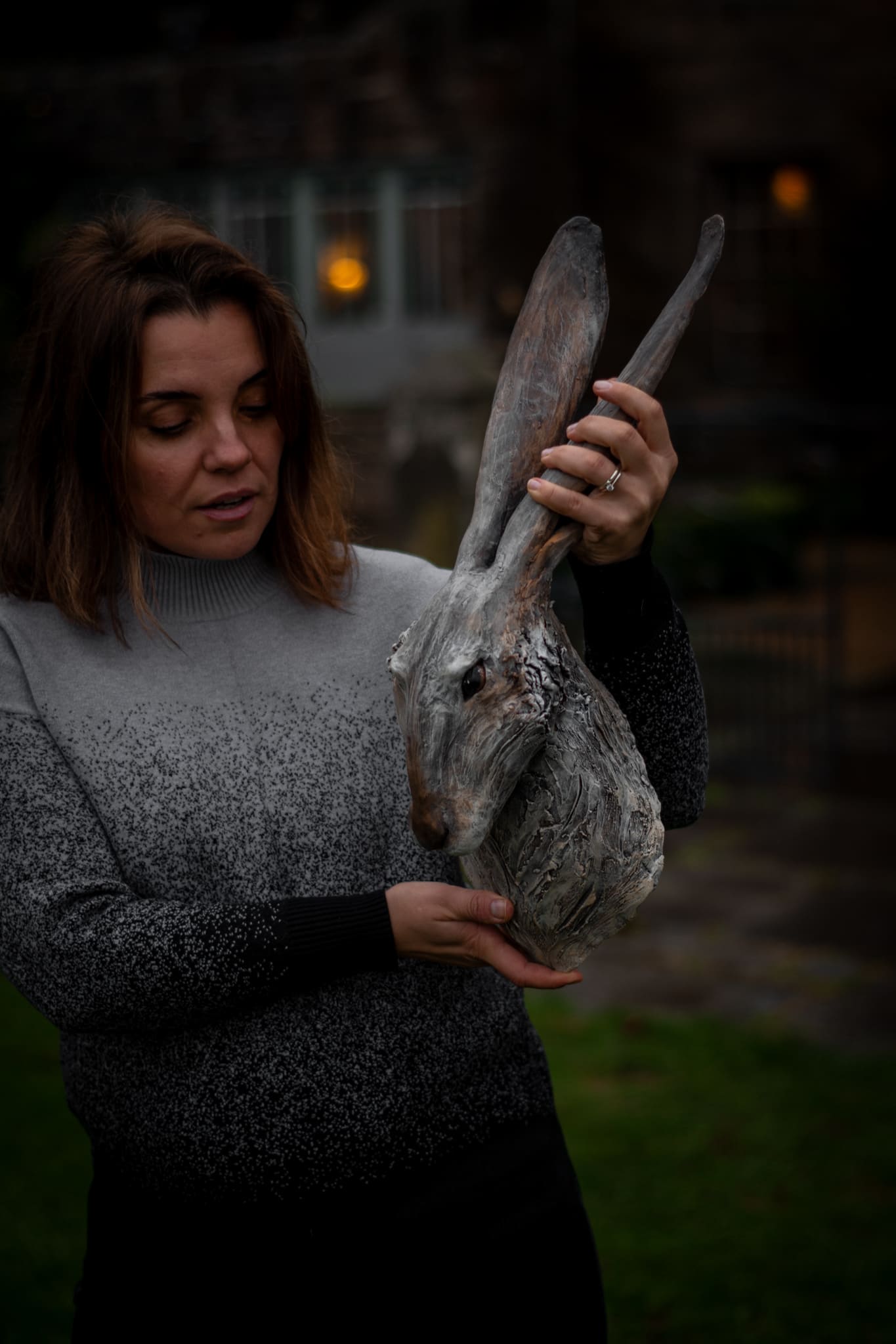 Olya Kivlin holding her hand-built hare sculpture in the garden