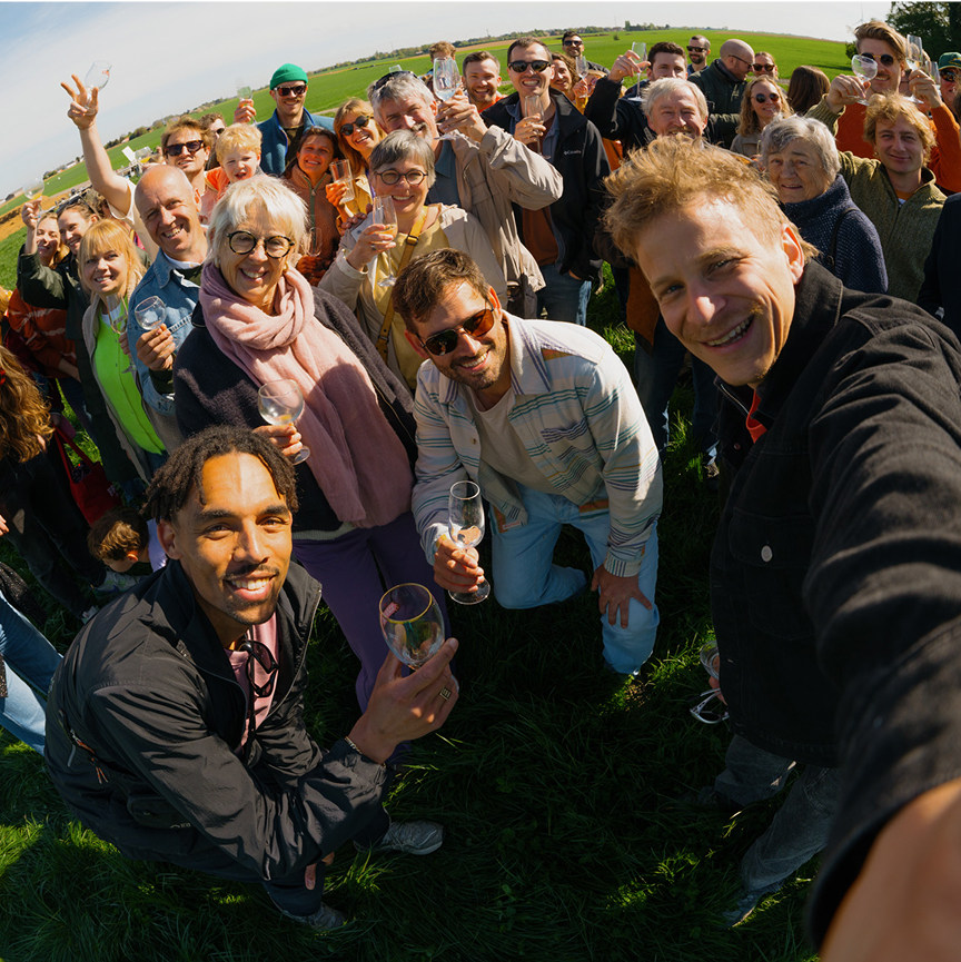 Een  groepsfoto van het Bolt-team, met een mix van mensen die samen lachen en een positieve sfeer uitstralen. Ze staan buiten in een groene omgeving. De foto straalt samenwerking en enthousiasme uit.