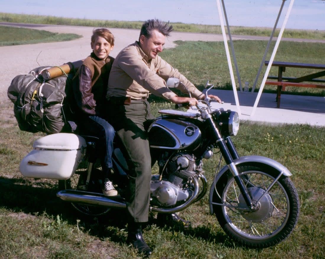 Colour photograph of Robert Pirsig and his son sat on a stationary motorcycle