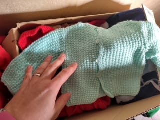 A hand-knitted jumper, so small that it's barely twice the size of my hand in the foreground for reference.