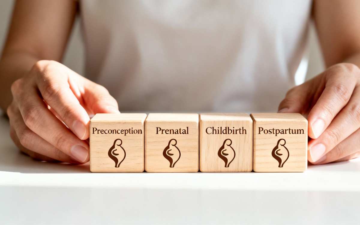 Close-up of hands arranging four wooden blocks depicting the stages of maternity: preconception, prenatal, childbirth, and postpartum.