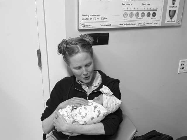 Doula holding swaddled newborn immediately after birth