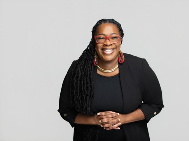 Portrait of Telisha Woodfin, founder of LIVLoved, smiling and standing in a professional setting.