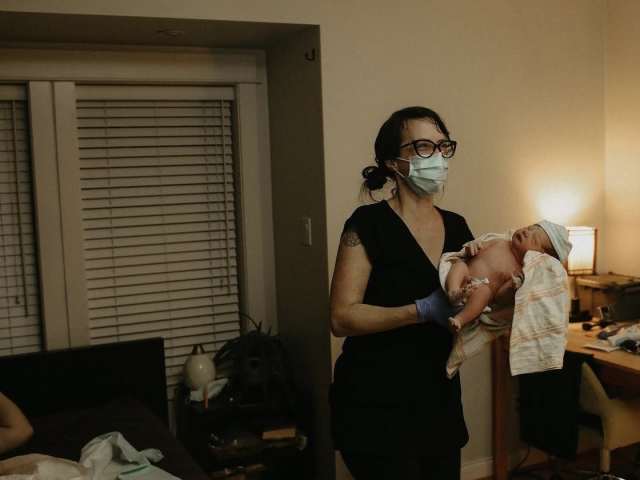 Holding a brand new baby to pass to mom while she repositions