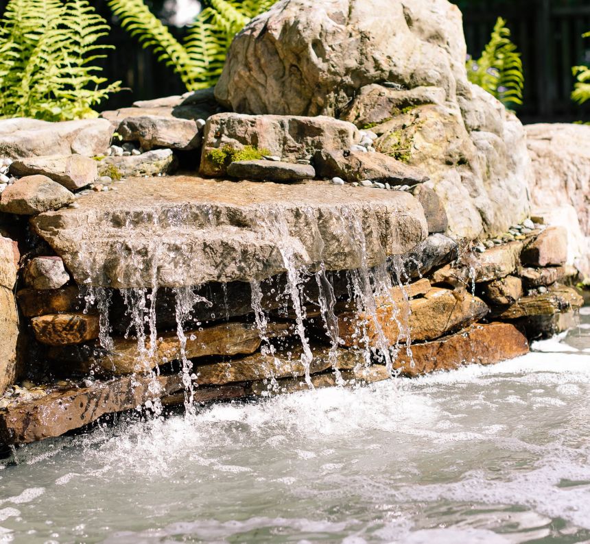 Stacked Stone water feature water fountain with green ferns in the background