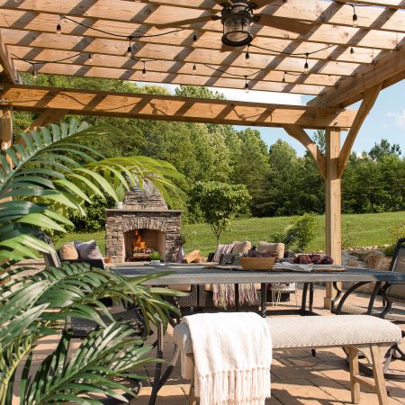 an outdoor fan is installed onto the pergola that also has strung lights over it