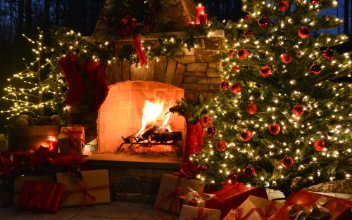 two white stockings hang on the wood burning fireplace mantle and above a wooden nativity scene